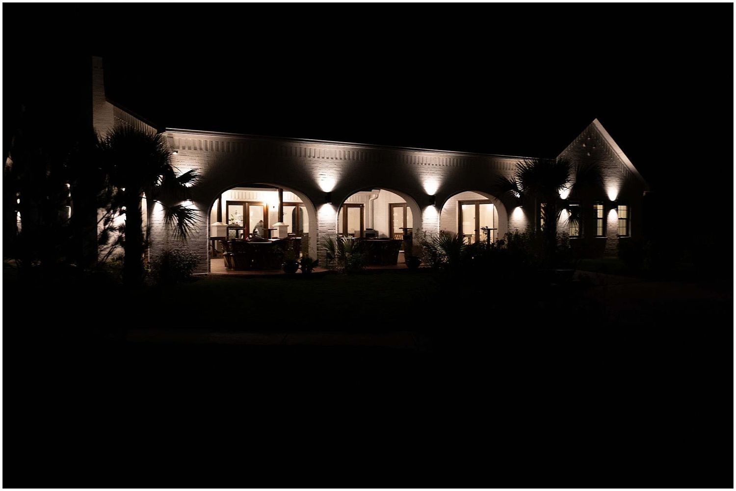 Silhouette of an illuminated wedding tent venue at night.