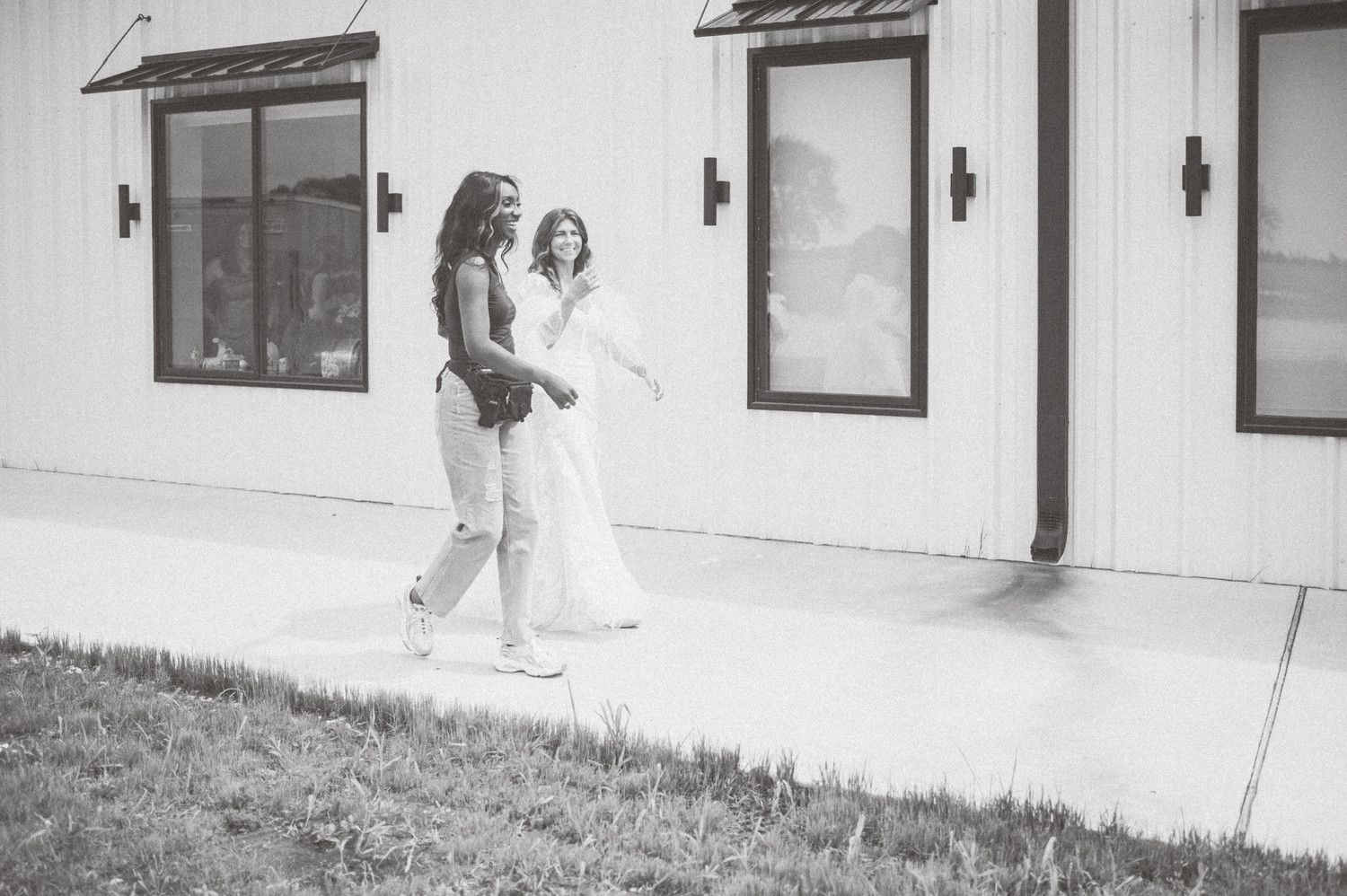 Black and white portrait session along a modern white building exterior with dramatic shadows.