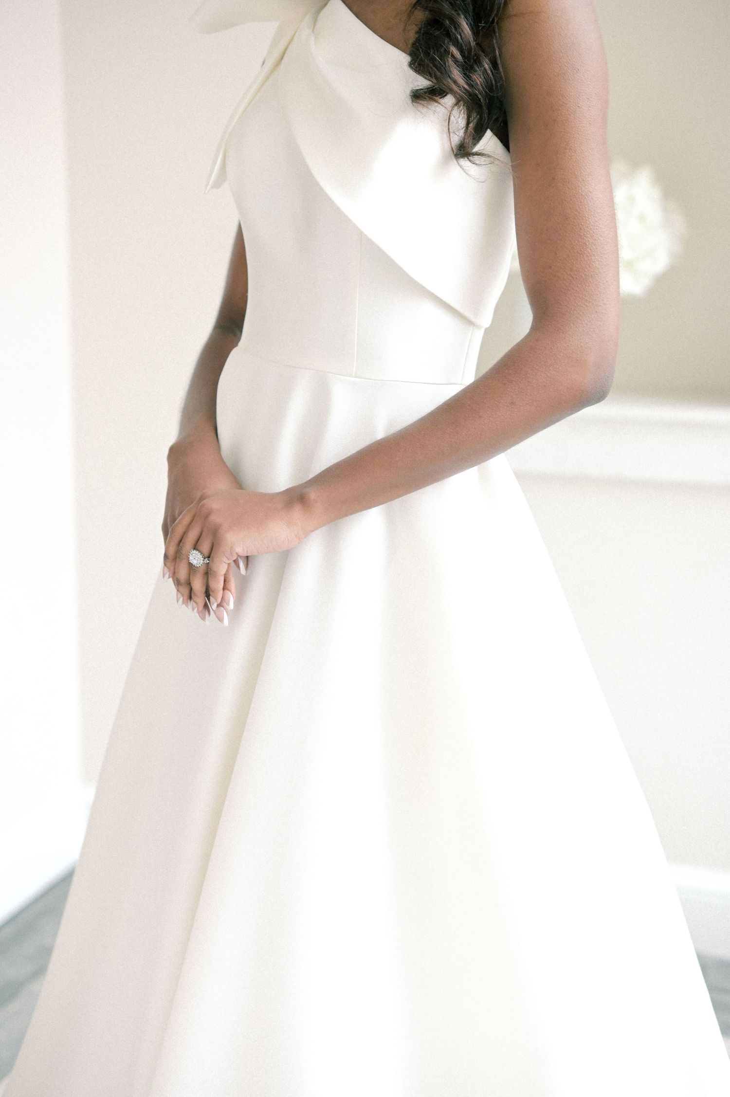 Elegant white wedding gown with architectural pleating and bow detail.