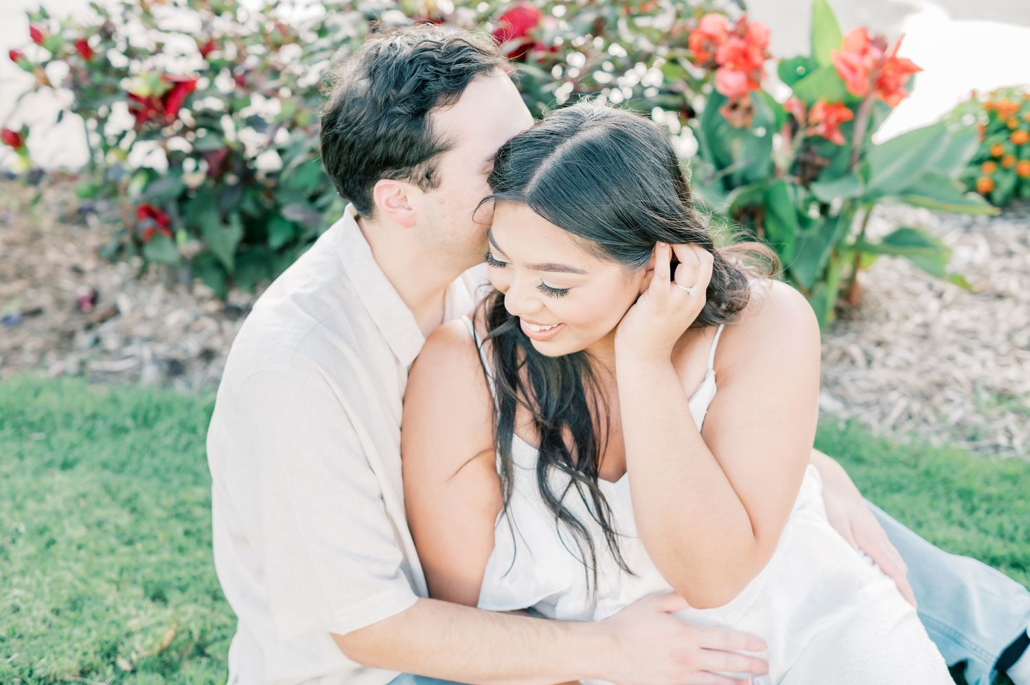 Candid garden photoshoot with vibrant red flowers and lush foliage creating a romantic backdrop.
