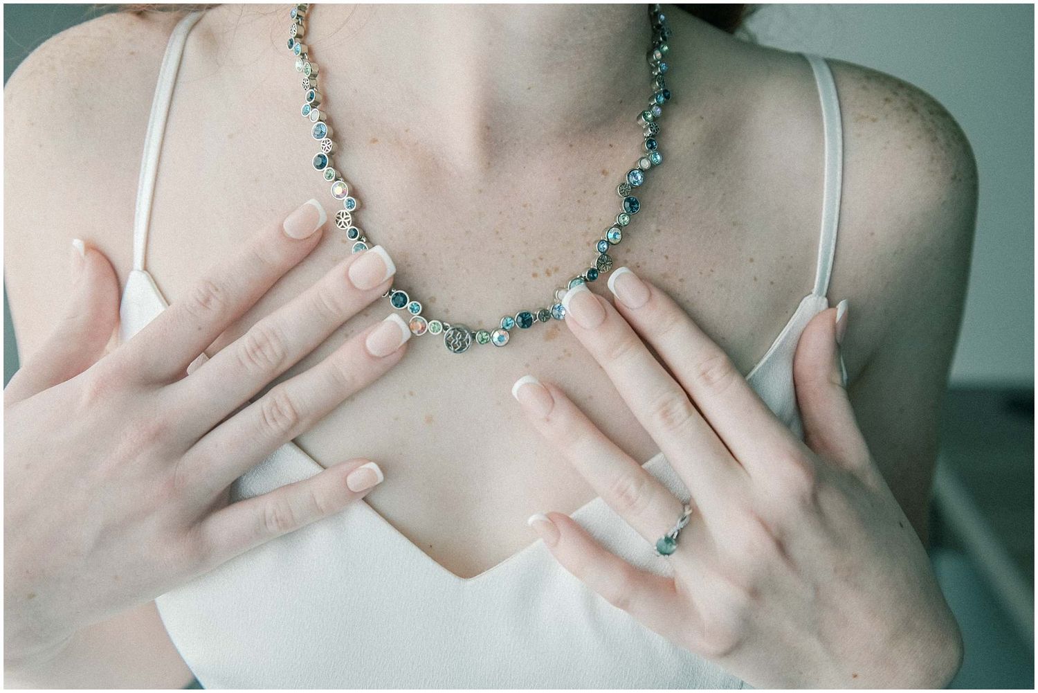 Close-up shots of hands touching a delicate blue beaded necklace against a soft background.