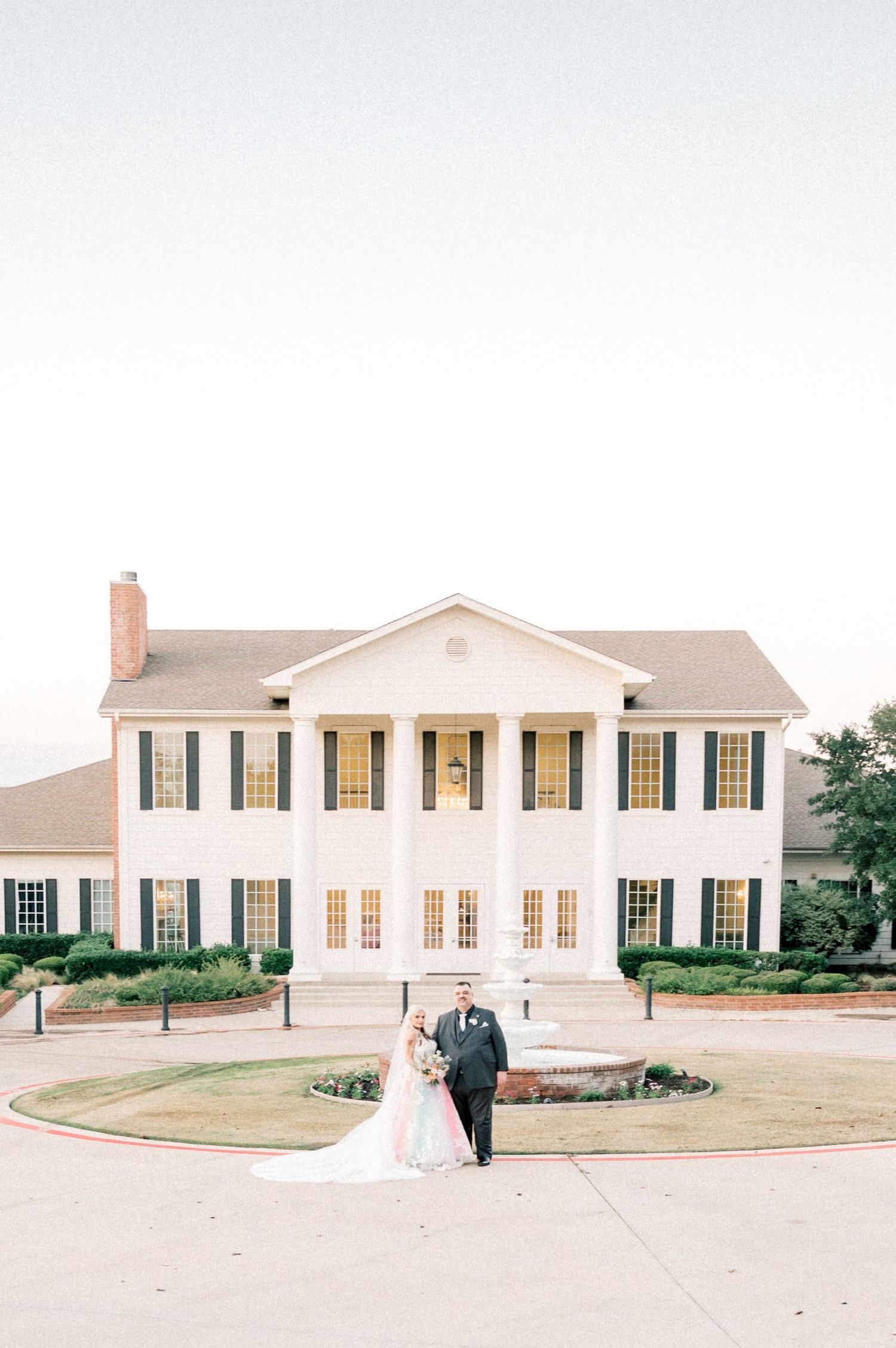 Elegant white colonial style venue with black shutters and manicured landscaping.