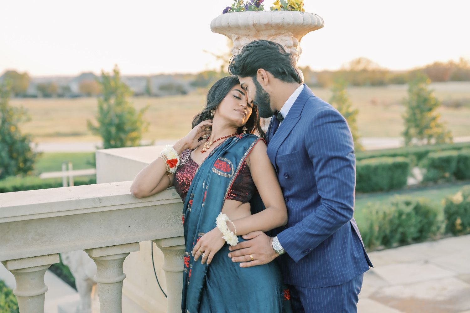 Couple shares tender moment on stone balcony during golden hour.