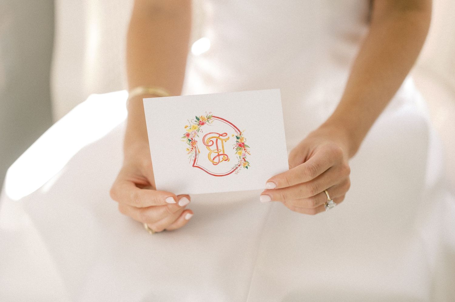 Close-up of hands holding a wedding invitation in soft natural lighting.