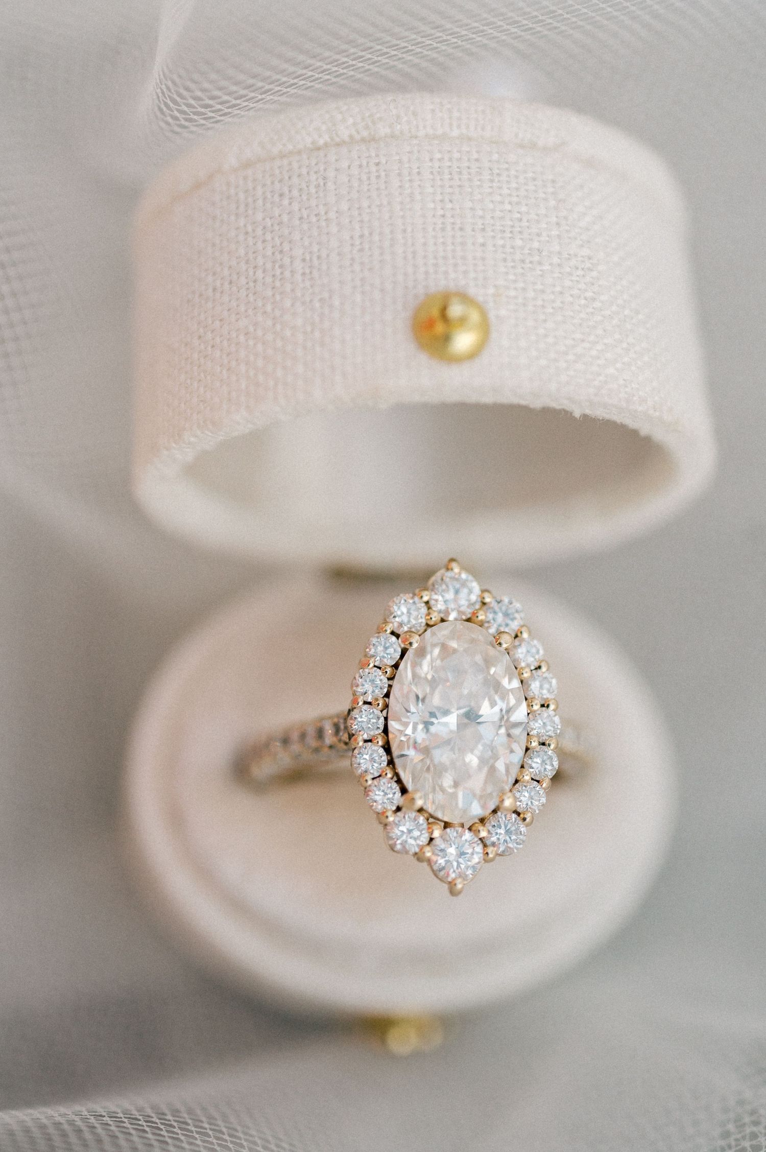 Elegant diamond engagement ring with halo setting displayed in white ring box.