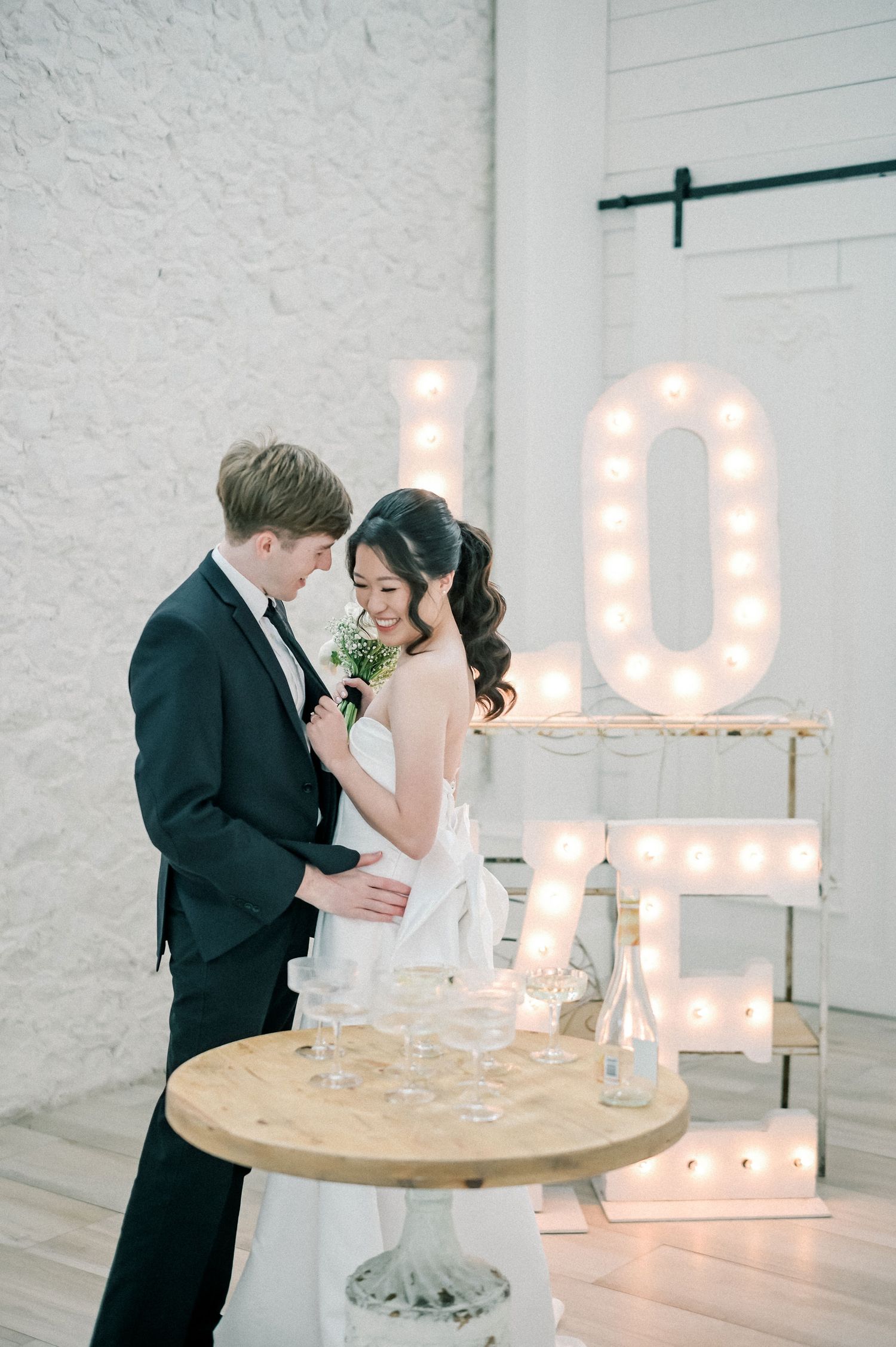 Wedding couple enjoying dessert at a reception table with illuminated marquee letters in the background.