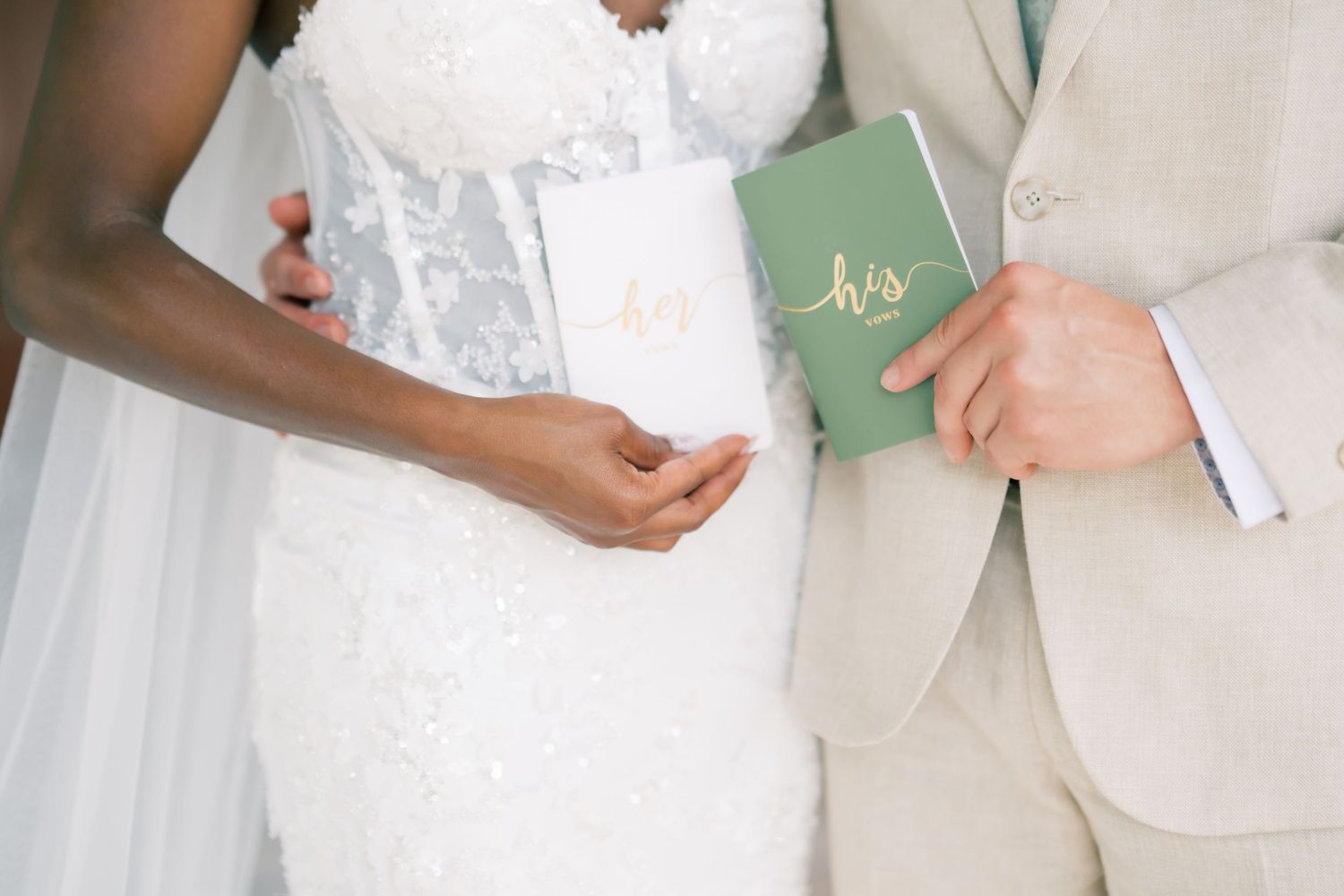 Bride and groom holding personalized his and hers vow books during outdoor wedding ceremony.