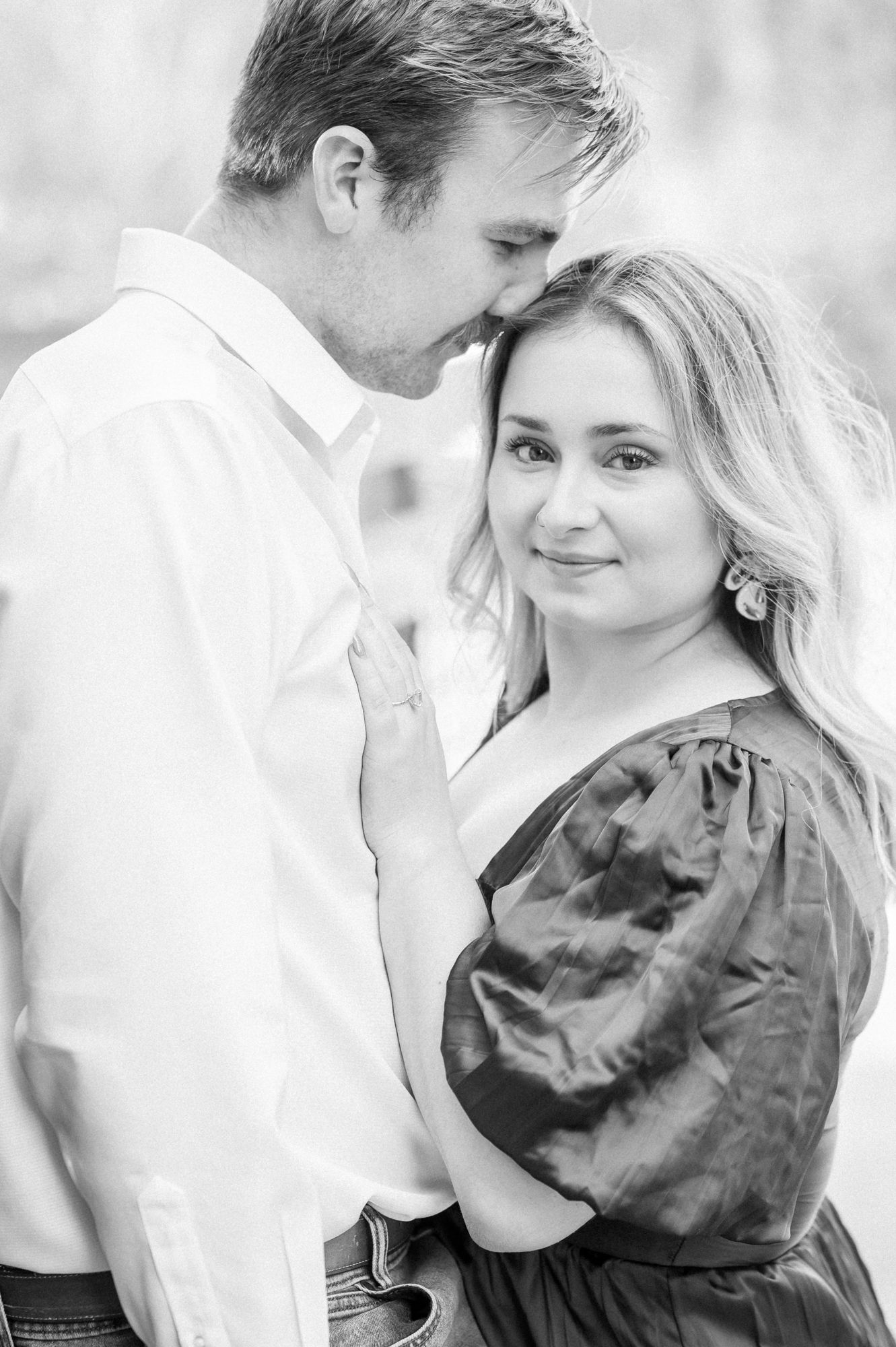 Black and white portrait of couple in tender embrace on outdoor walkway.