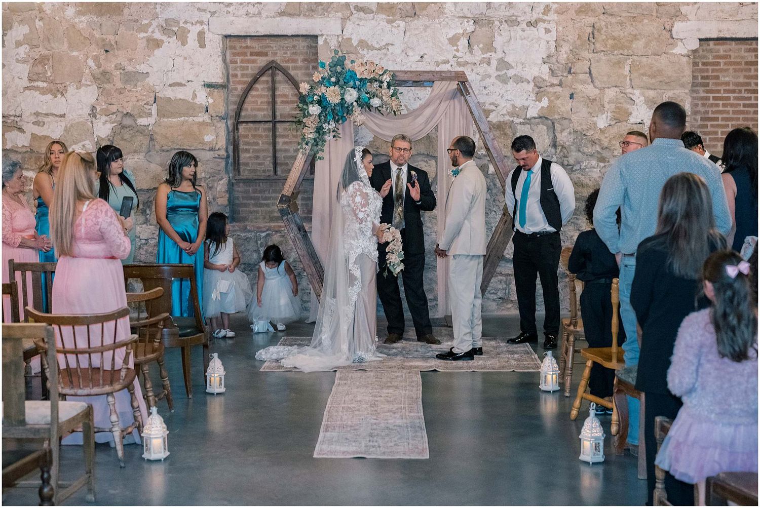 Wedding celebration in a rustic brick venue with guests gathered for the ceremony.