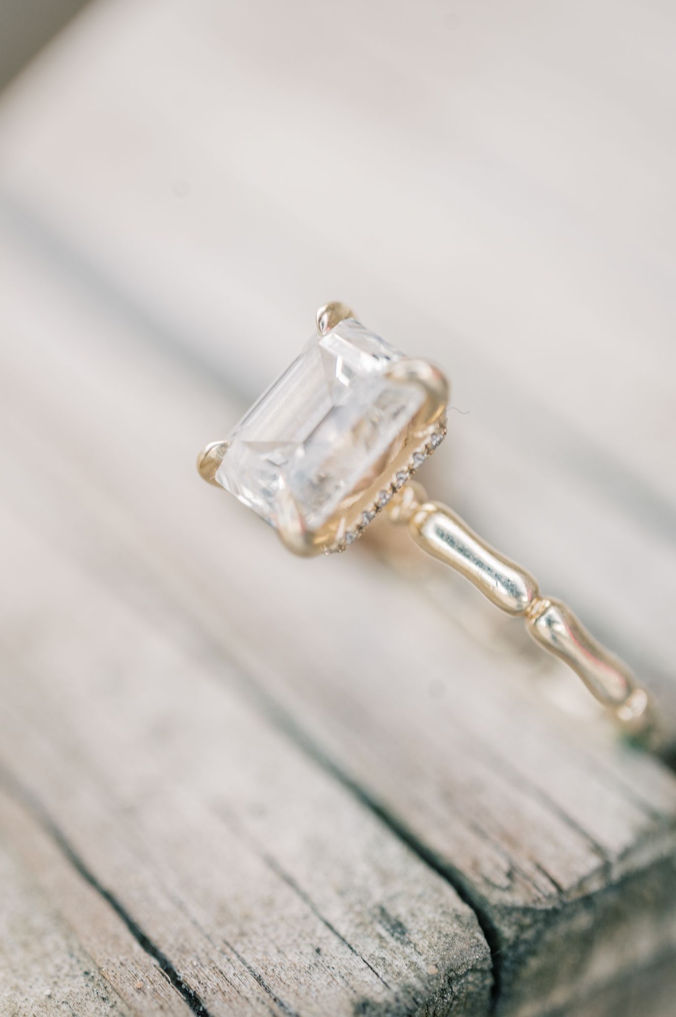 Side profile of an elegant diamond engagement ring showcasing its prong setting on rustic wood.