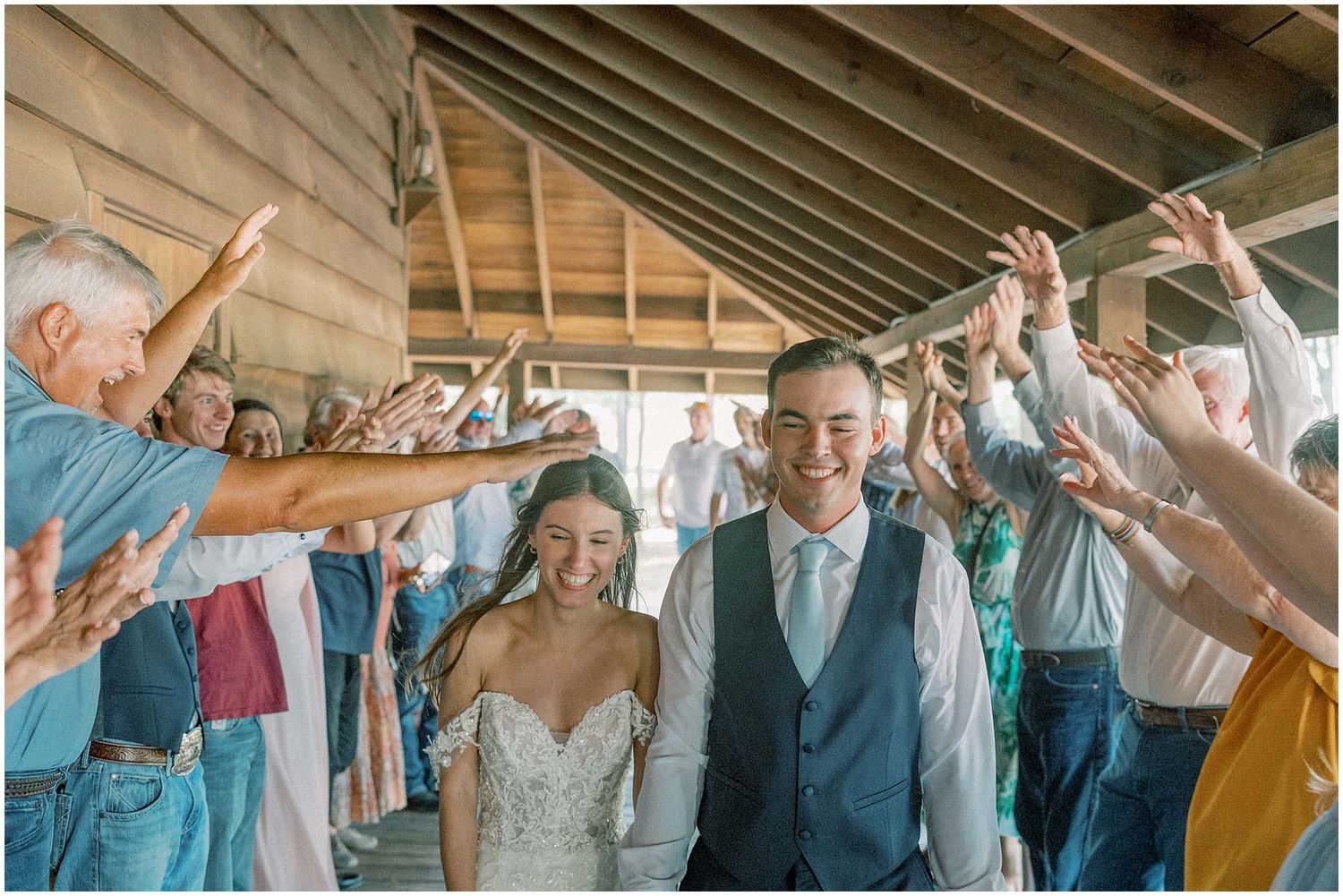 Wedding party dancing and celebrating with raised arms on a dance floor at a reception.