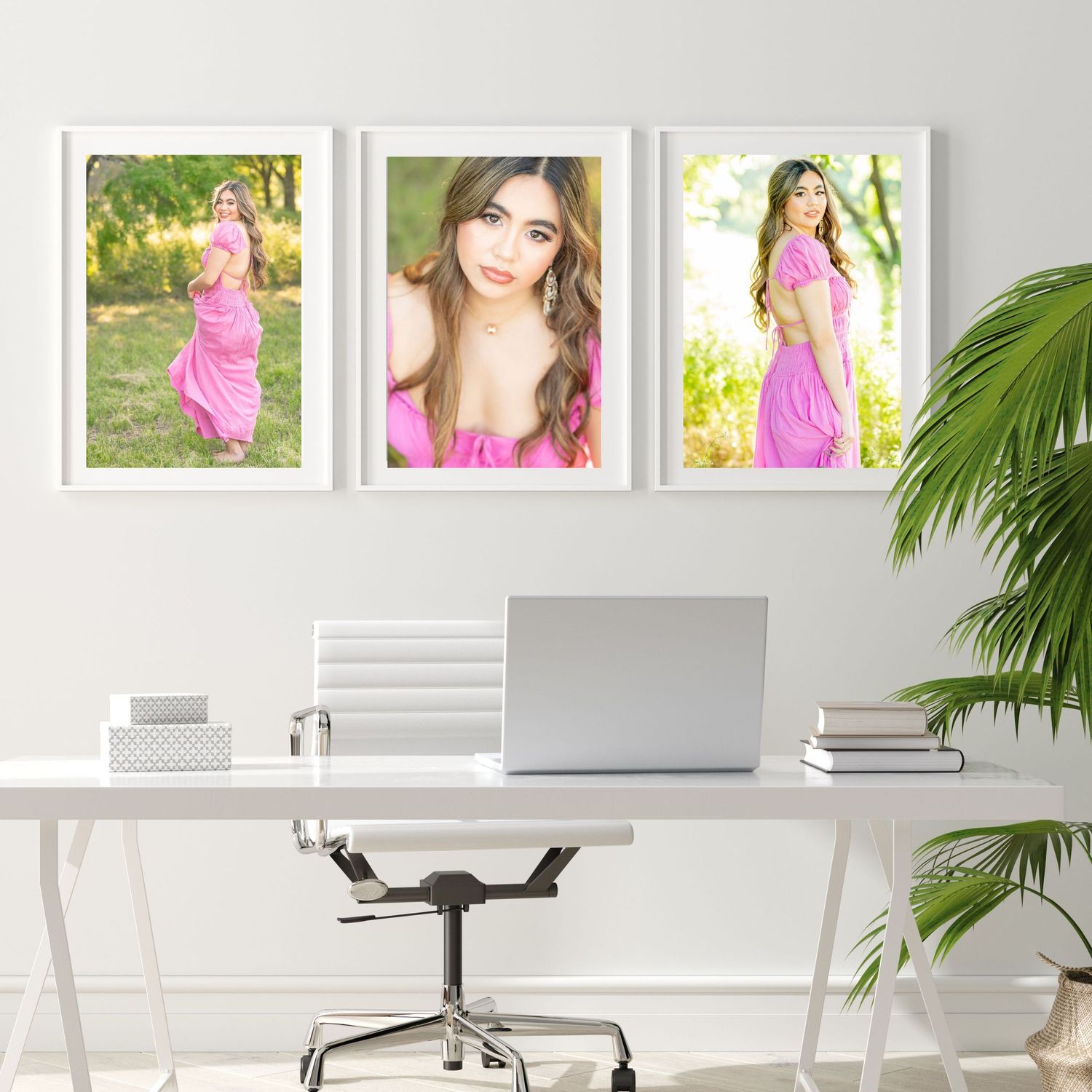 Three framed senior portraits of a girl in a pink dress displayed above a white desk with a laptop in a bright home office.
