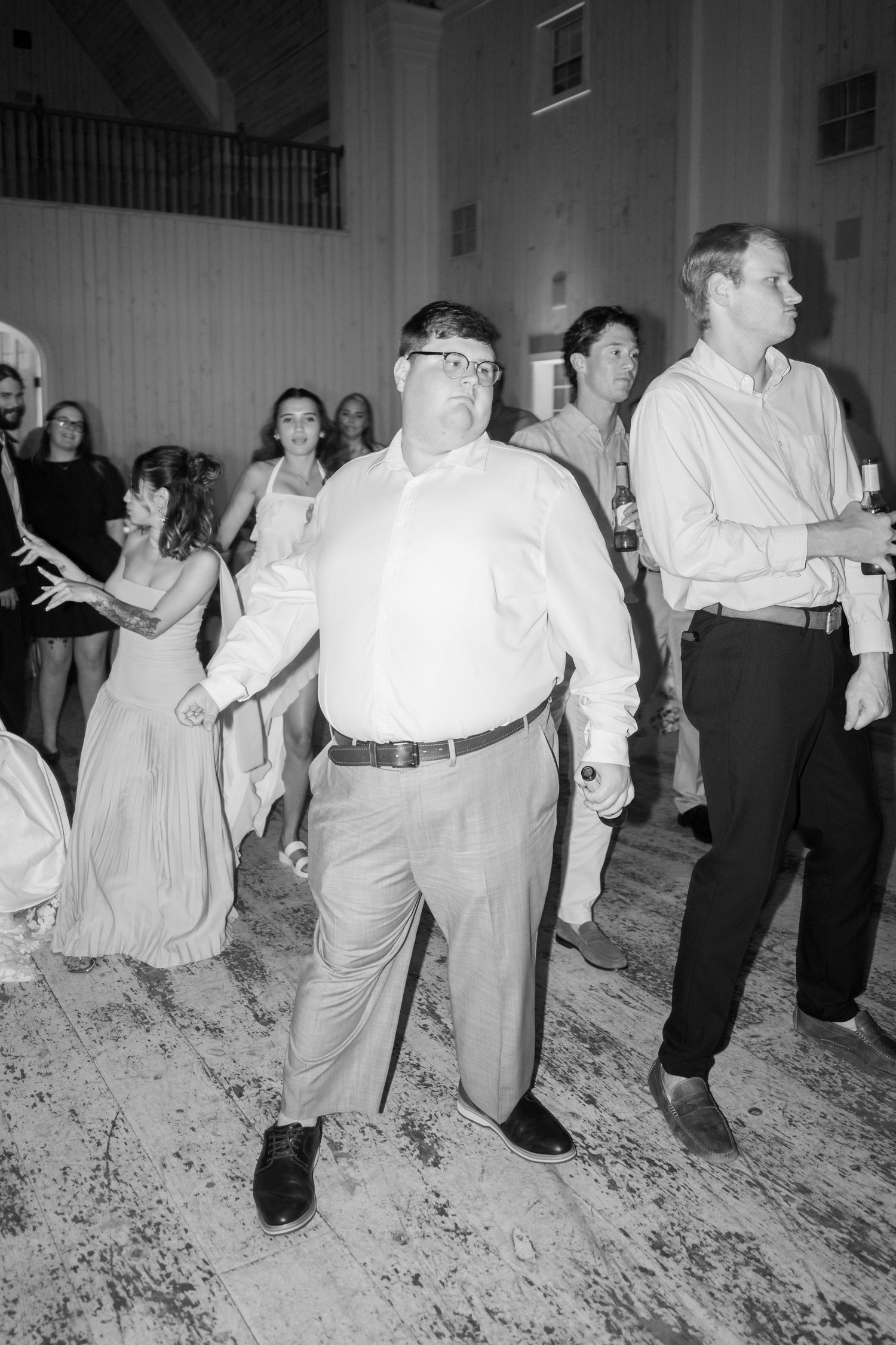 Wedding guests dancing joyfully on the dance floor during a lively reception celebration.
