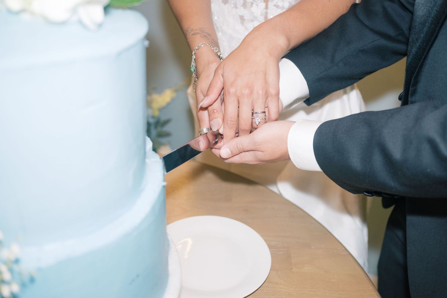 Bride and groom cutting light blue tiered wedding cake together at reception celebration.