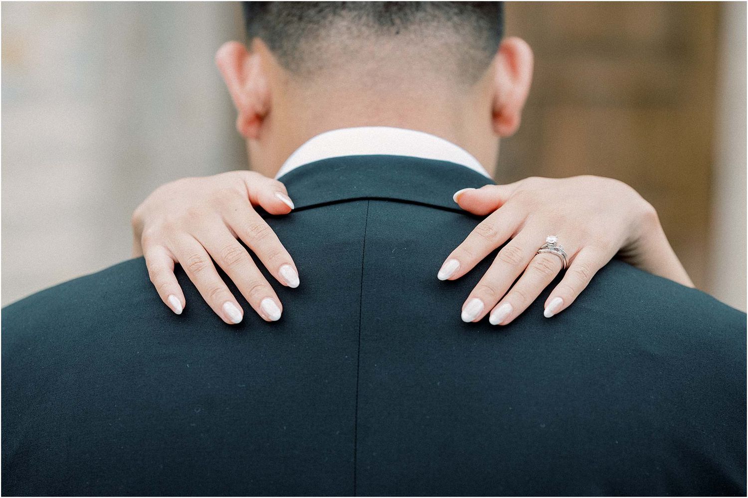 Close-up detail shots of hands resting on a dark suit jacket.