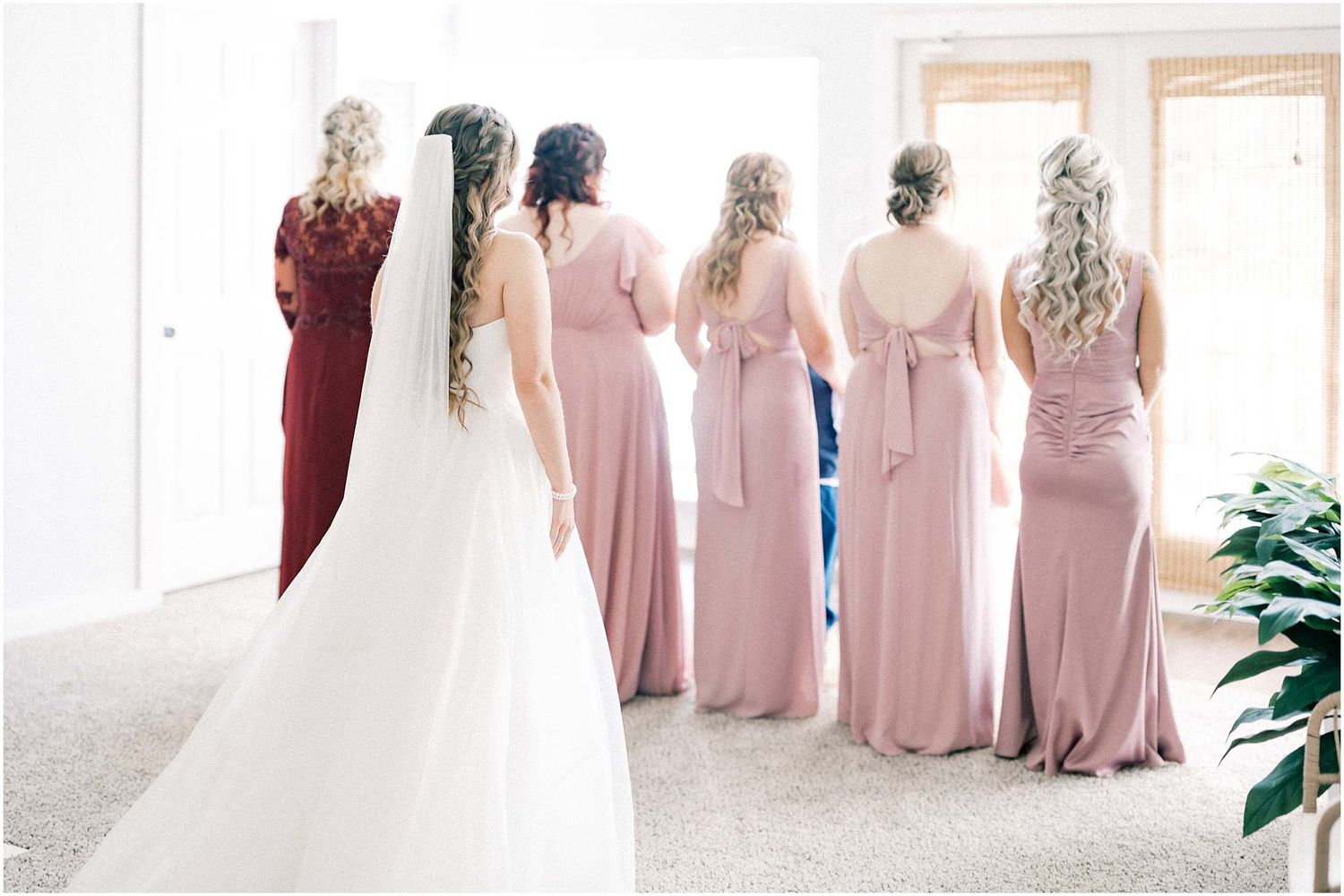 Wedding party in pink bridesmaid dresses standing together.