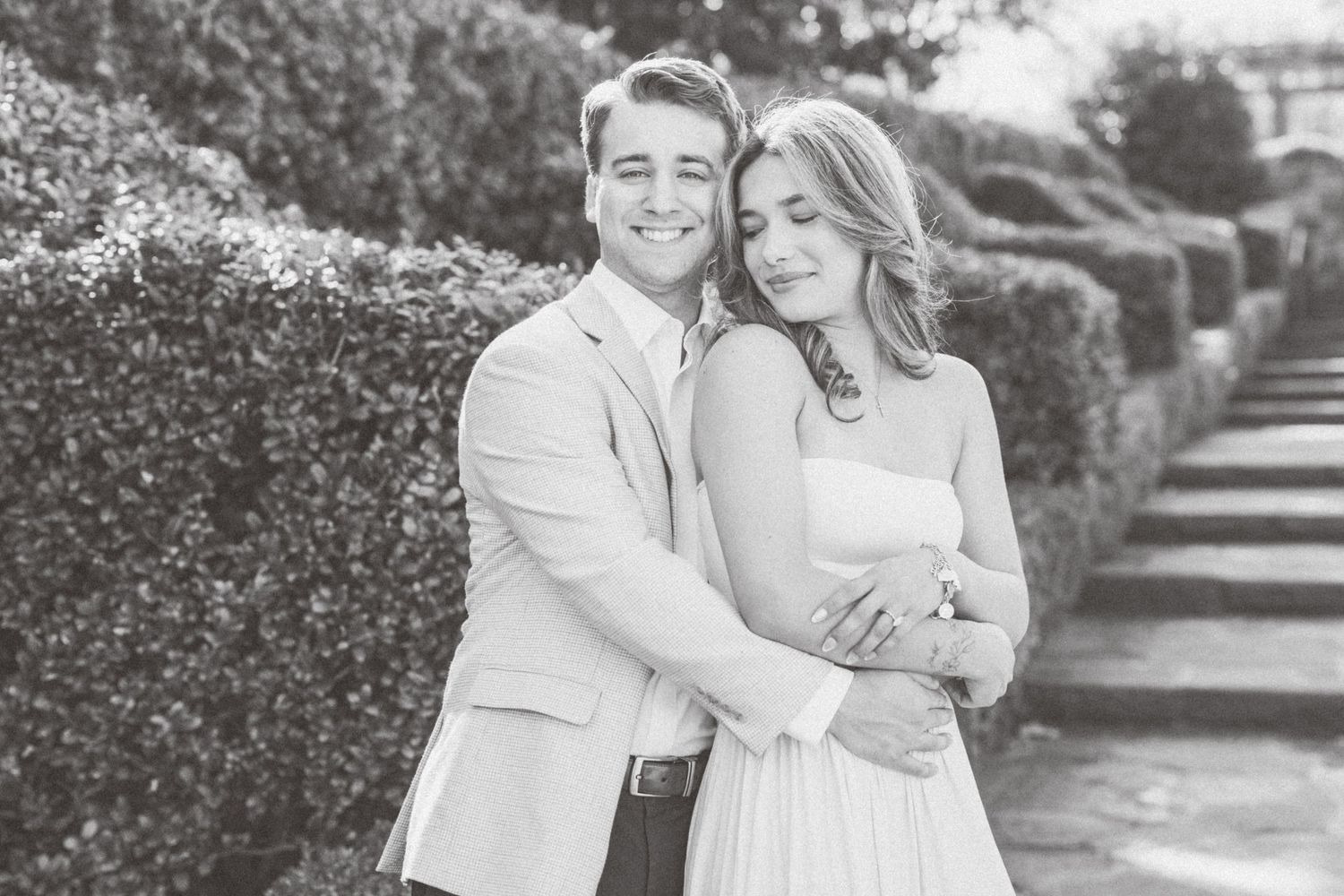A couple shares tender moments in a garden setting during an engagement photo session.
