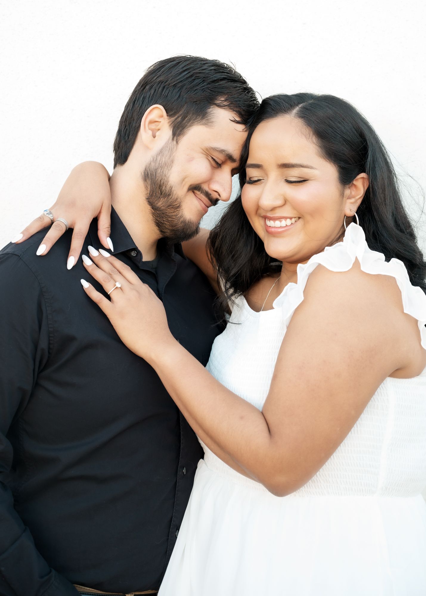 A tender moment between a couple in coordinated black and white outfits against a bright background.