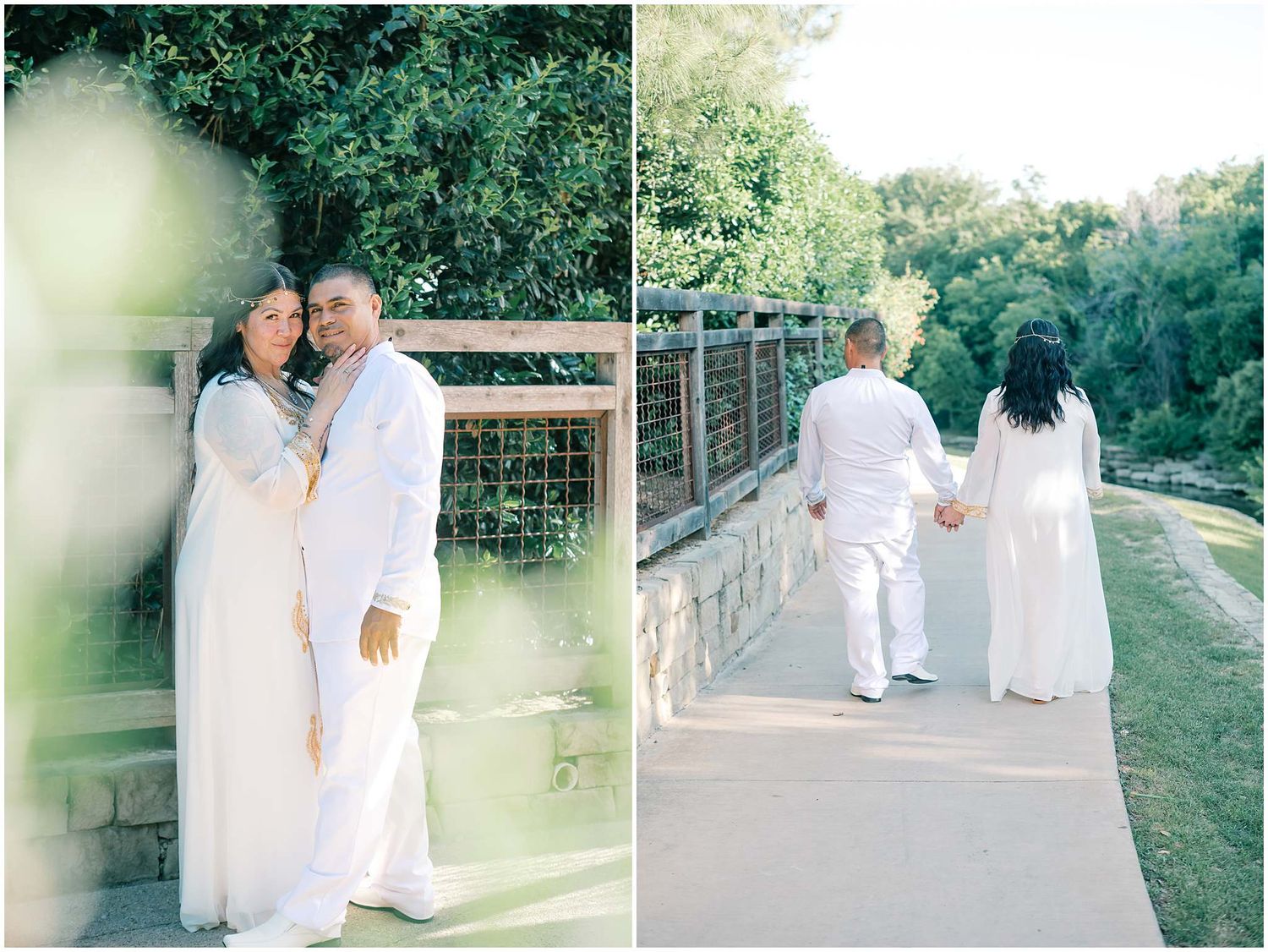A couple in all-white attire walks together through a lush green garden setting.