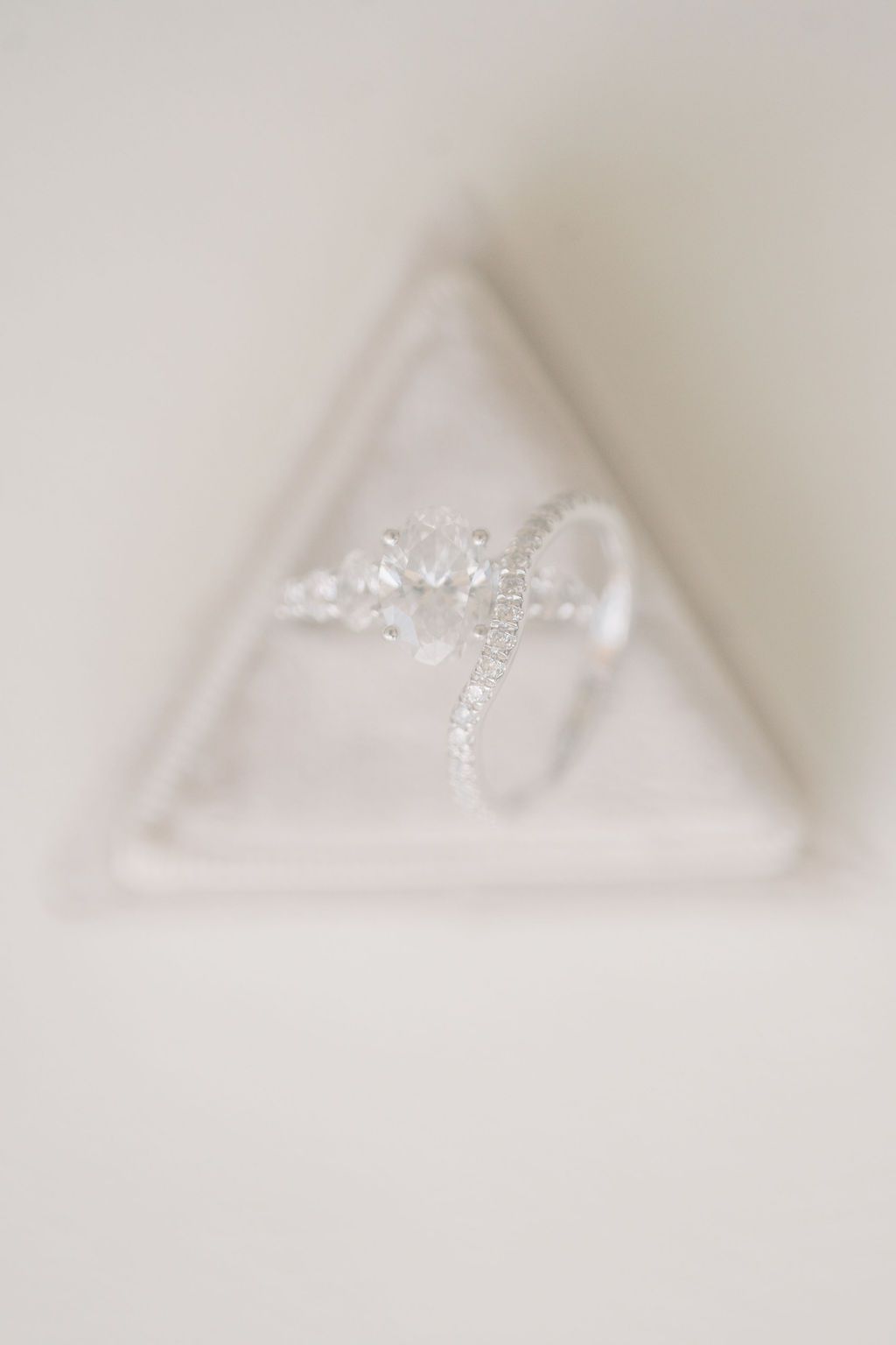 Elegant diamond engagement ring with cluster setting displayed in a triangular white velvet ring box.