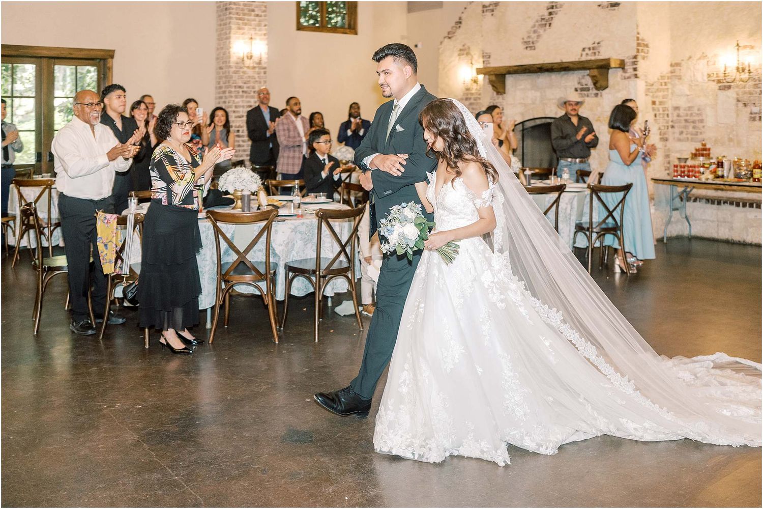 Wedding reception first dance with guests watching in elegant venue with chandelier lighting.
