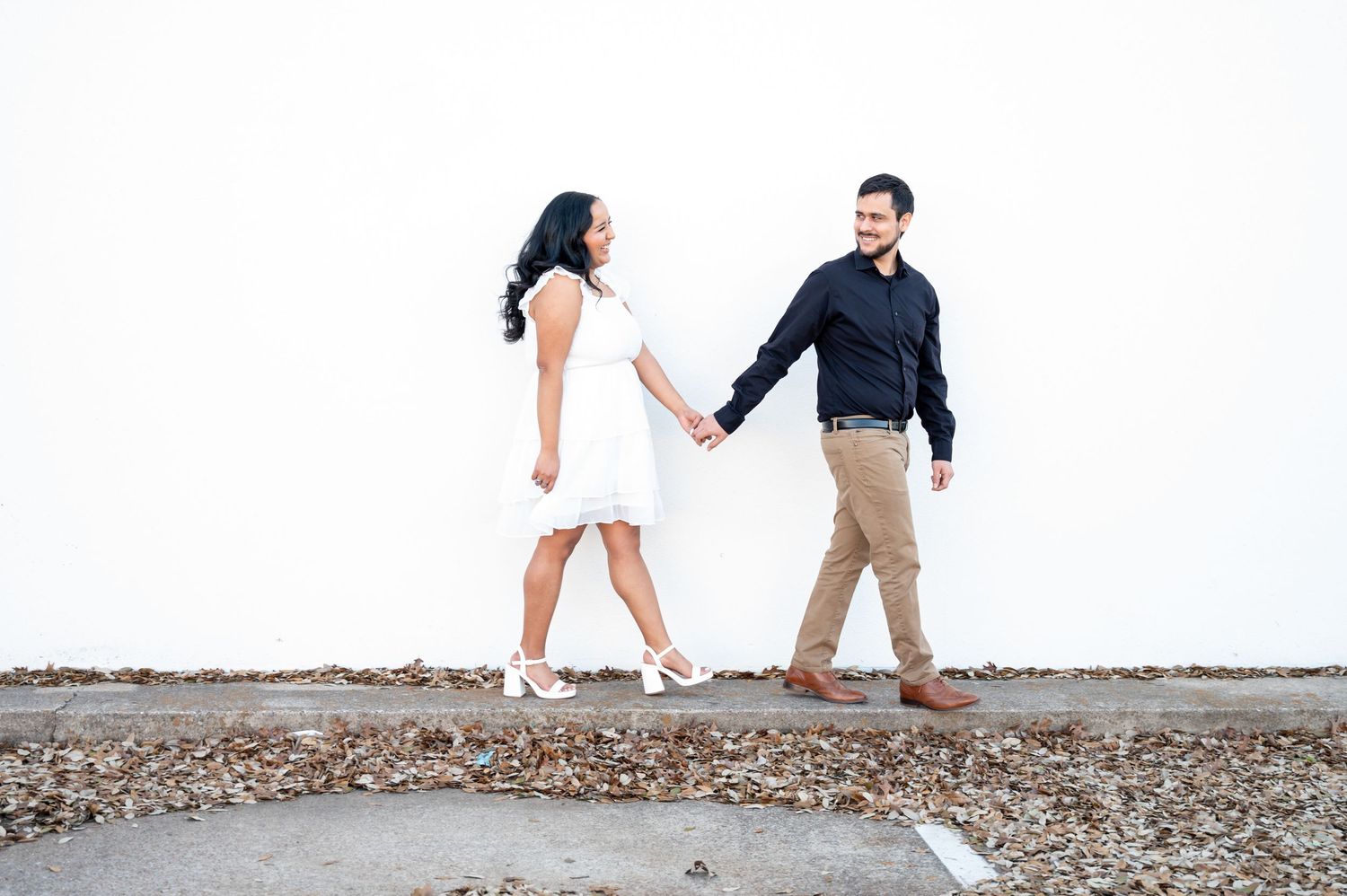 Couple walking and playing together on a rocky beach shoreline.