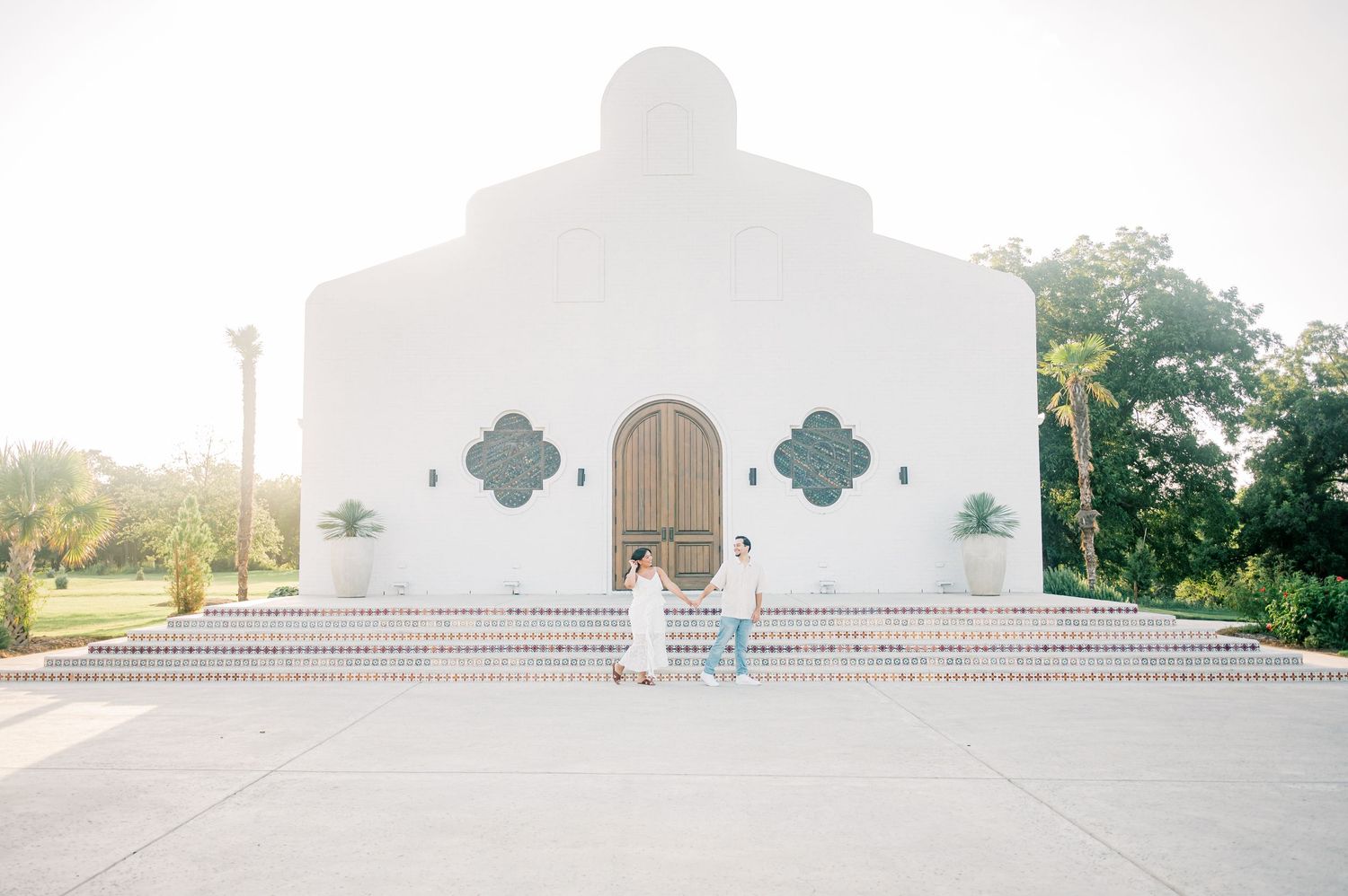 White Spanish mission style church building with decorative crosses and arched doorways in golden sunlight.