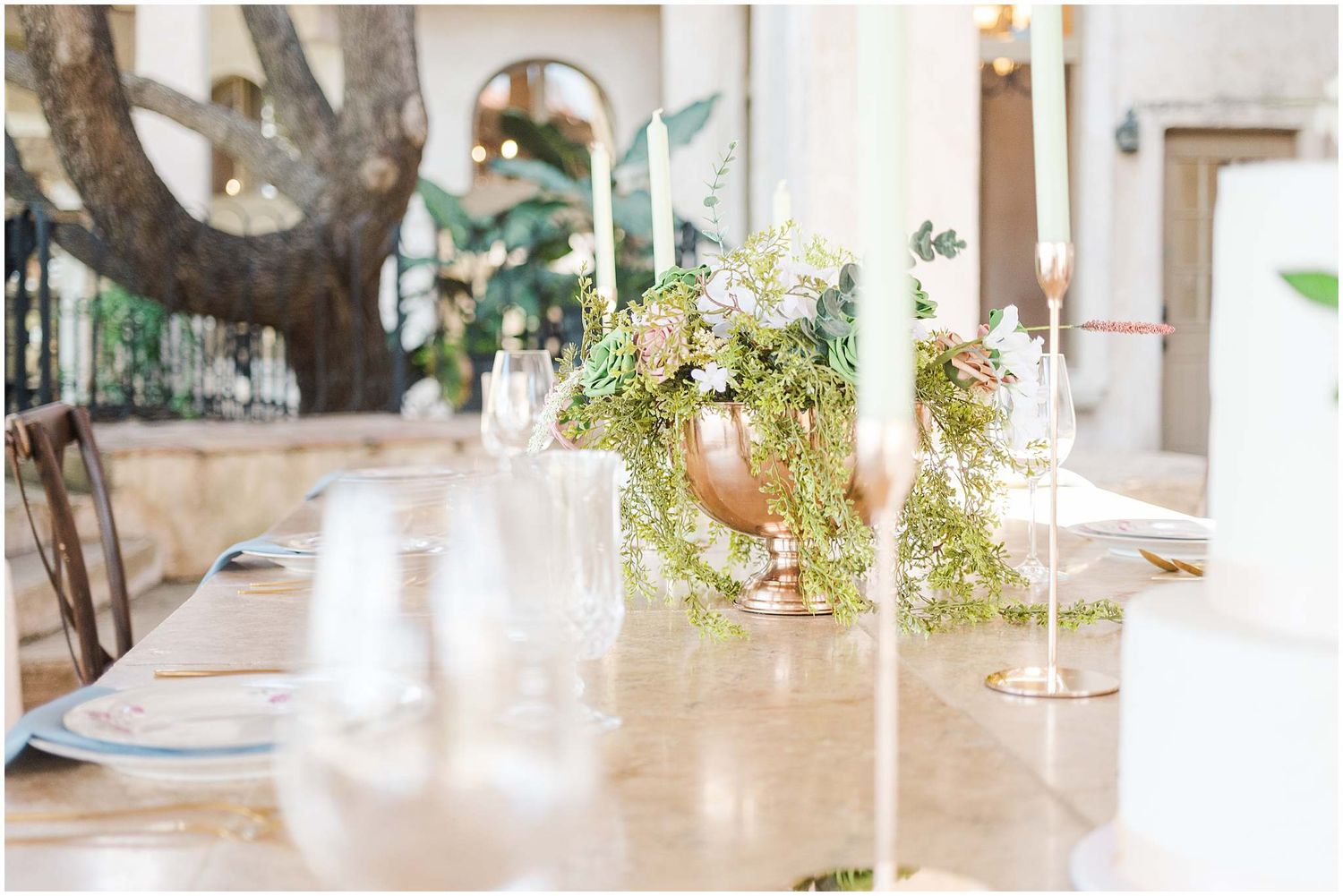 Elegant indoor venue decorated with natural greenery and white candles for celebration.