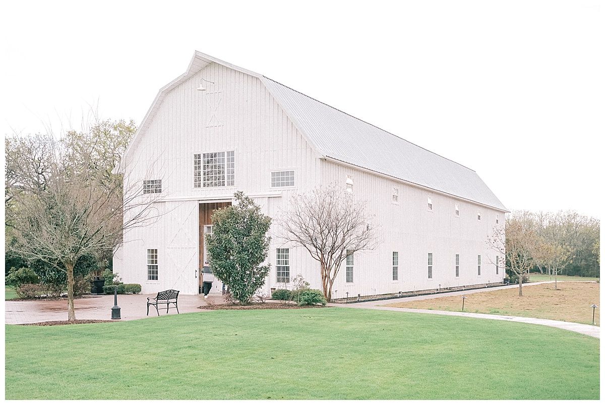 A series of white barns and farm buildings photographed from different angles on a grassy rural property.
