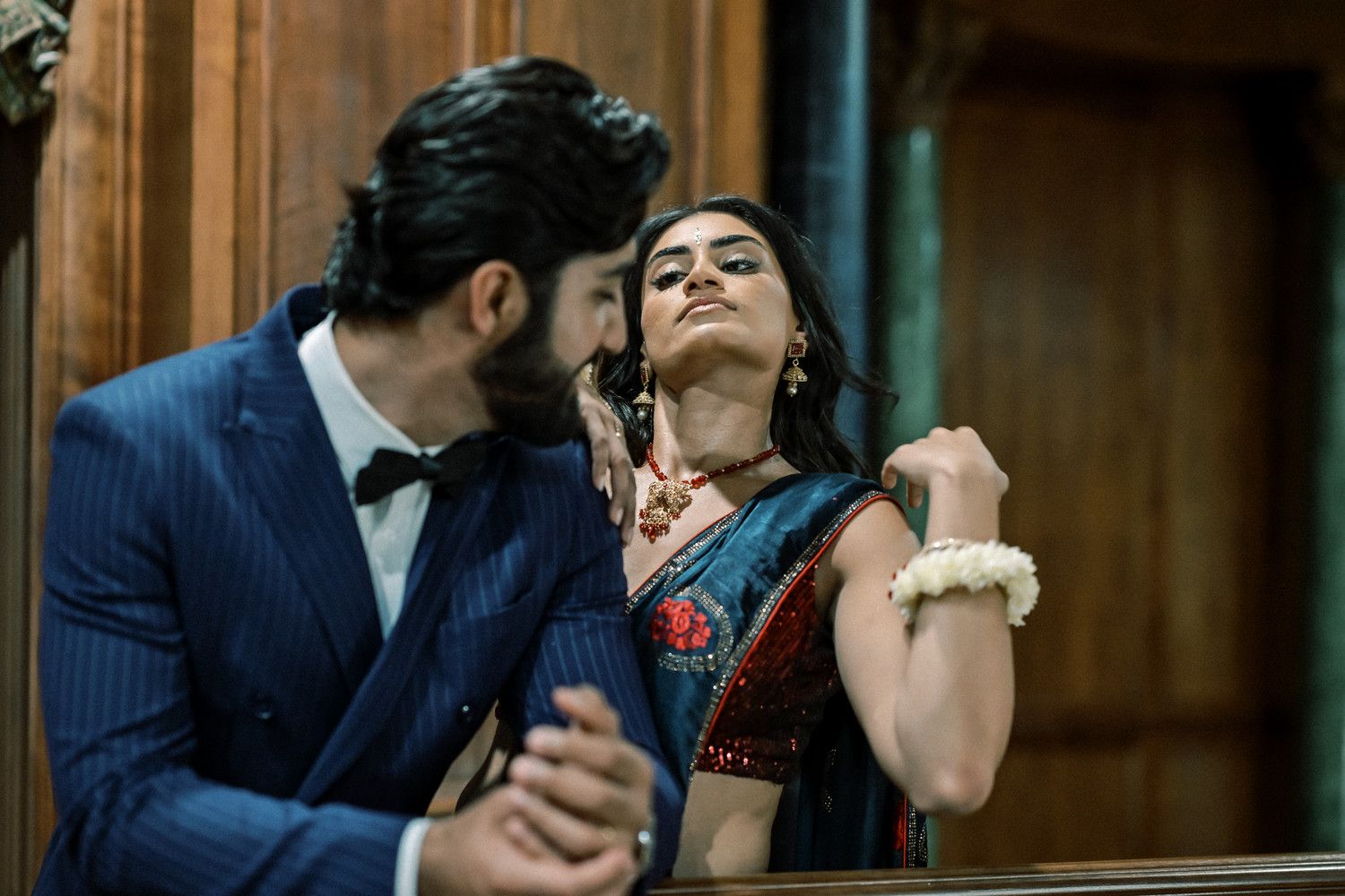 Intimate moment captured between couple in formal attire against wood-paneled interior.