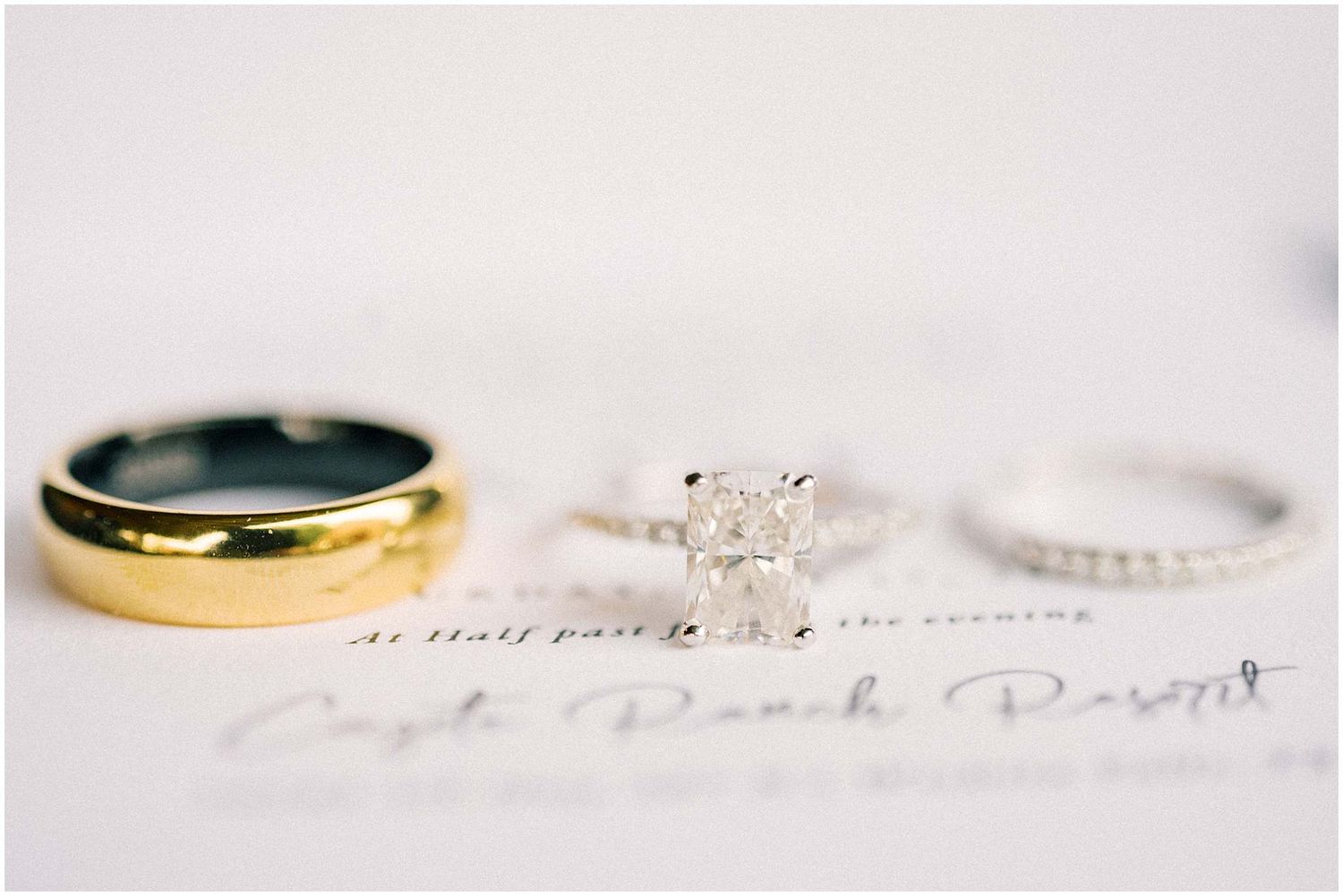 Close-up of wedding rings and handwritten note on white background.