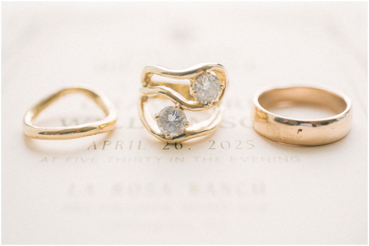 Close-up of gold wedding rings and engagement ring with diamonds on white background.