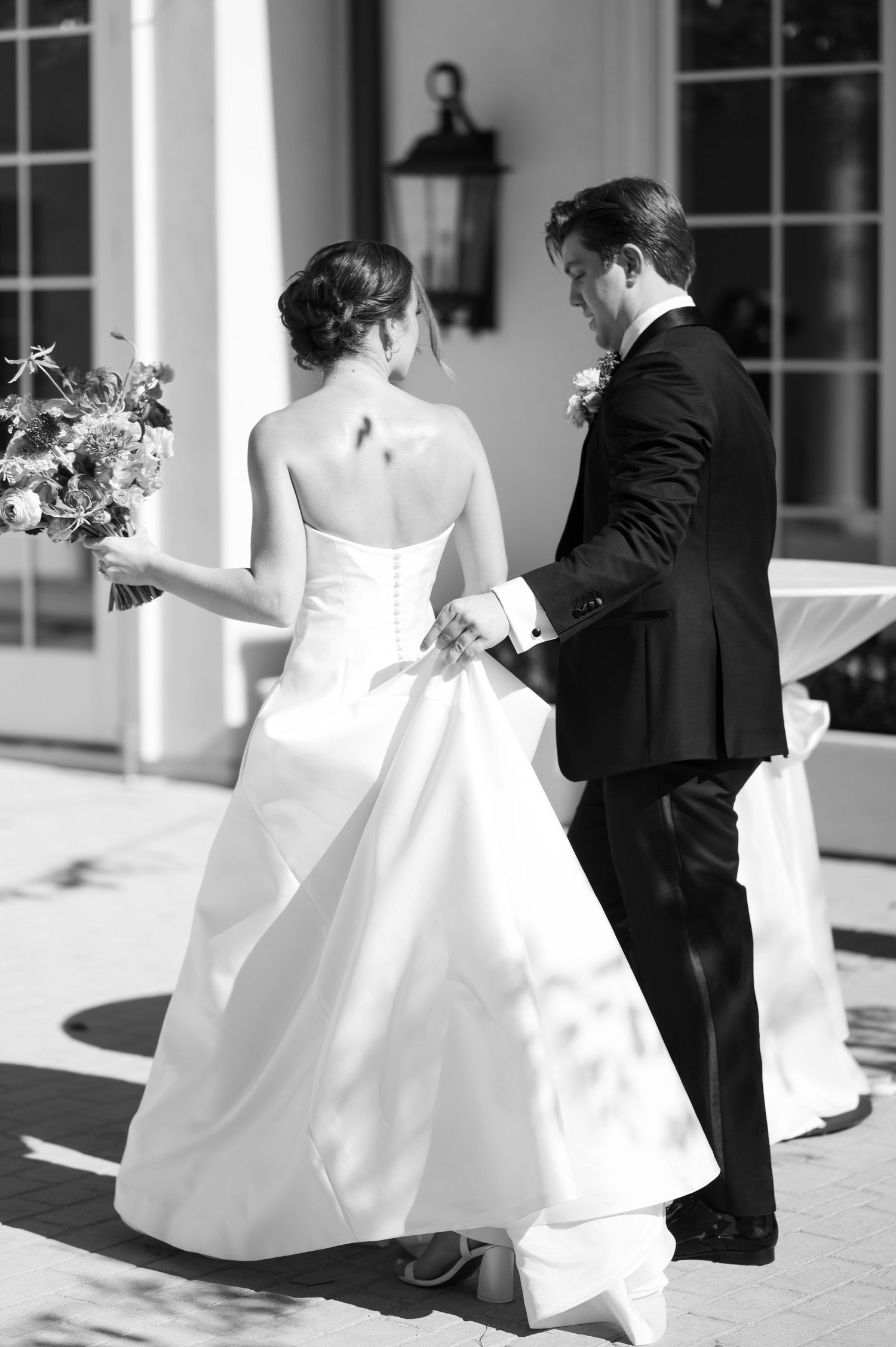 Elegant wedding couple dancing and twirling on a sunny outdoor terrace.