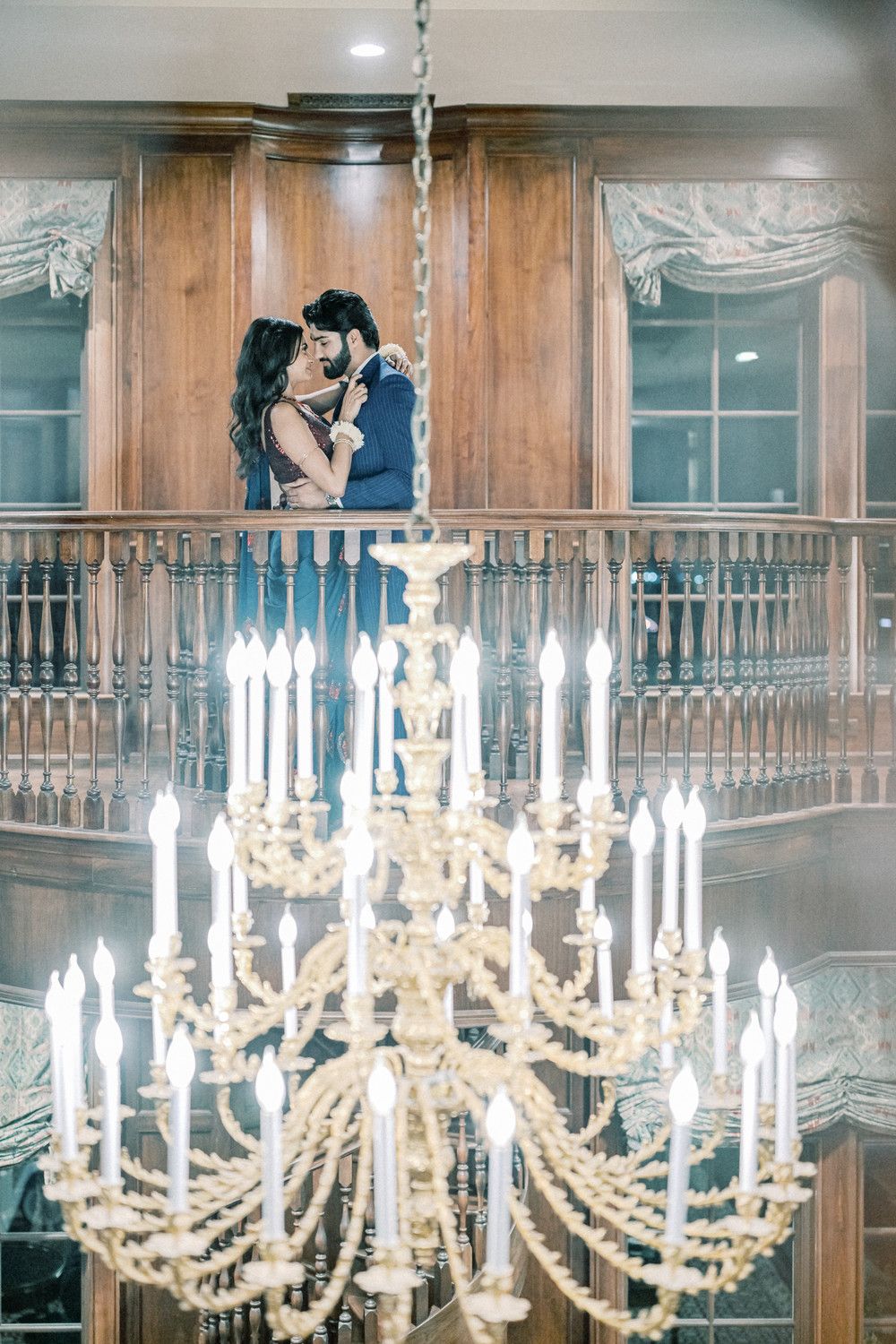 Multiple crystal chandeliers hang in sequence along an ornate wooden interior hallway.