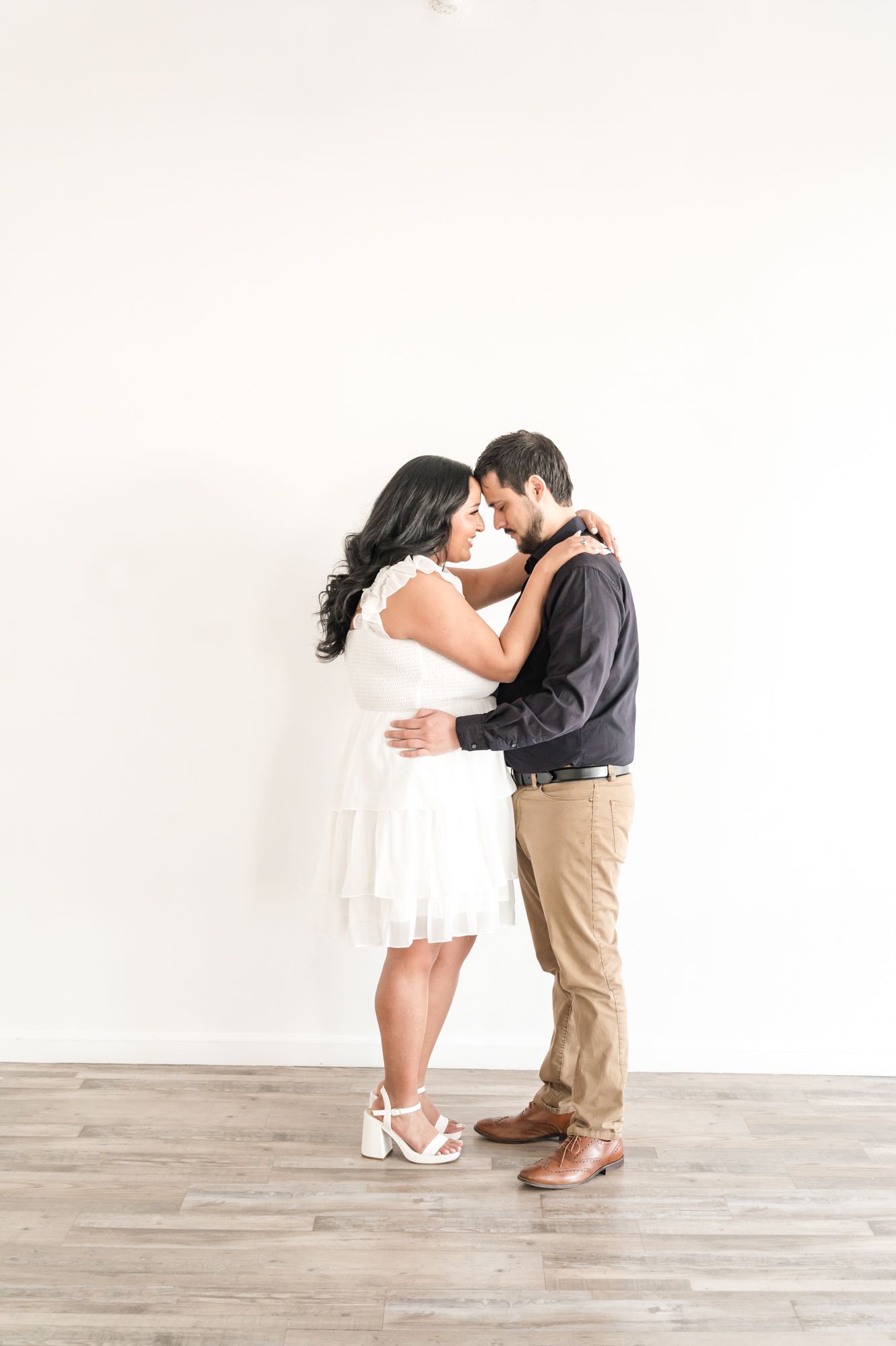 A romantic couple in coordinated black and white outfits share intimate poses against a white background.