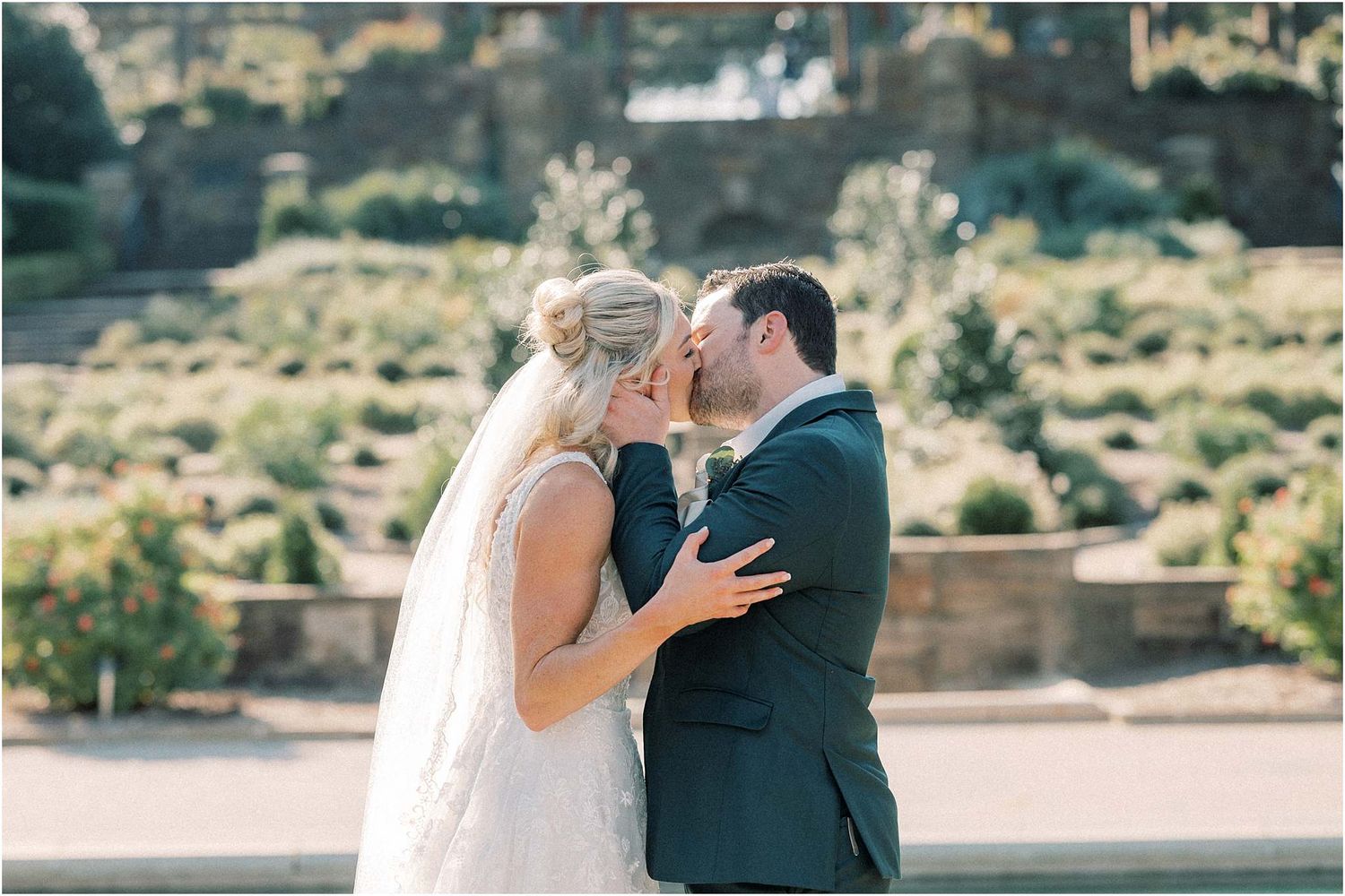 Intimate wedding moment captured in front of a scenic terraced garden backdrop.