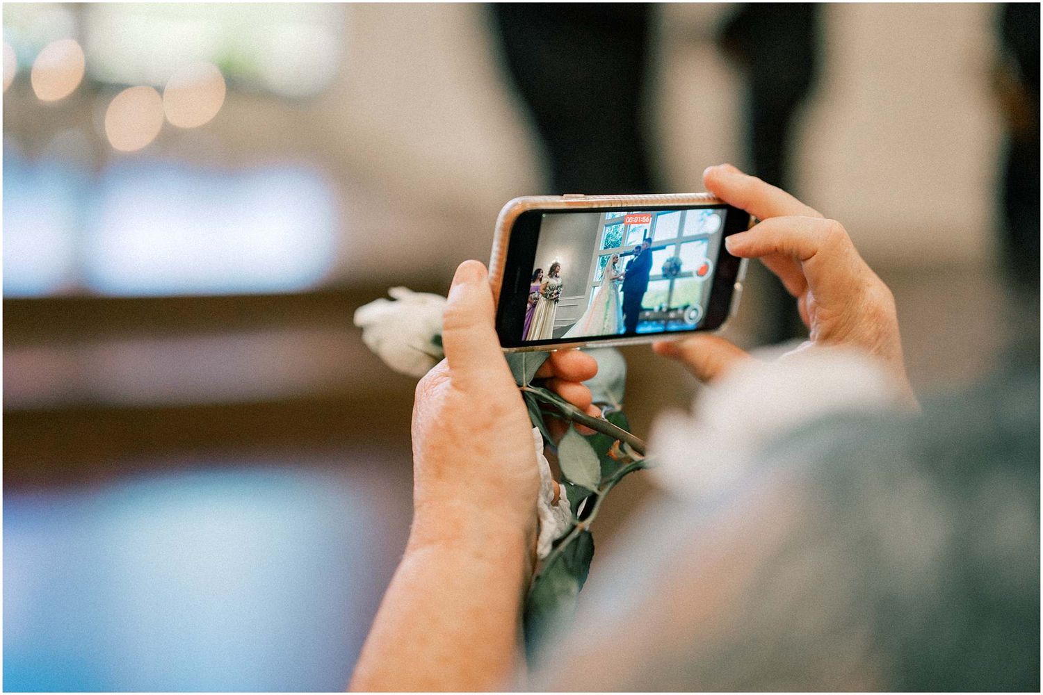 Guest taking photos with smartphone at an indoor wedding venue.