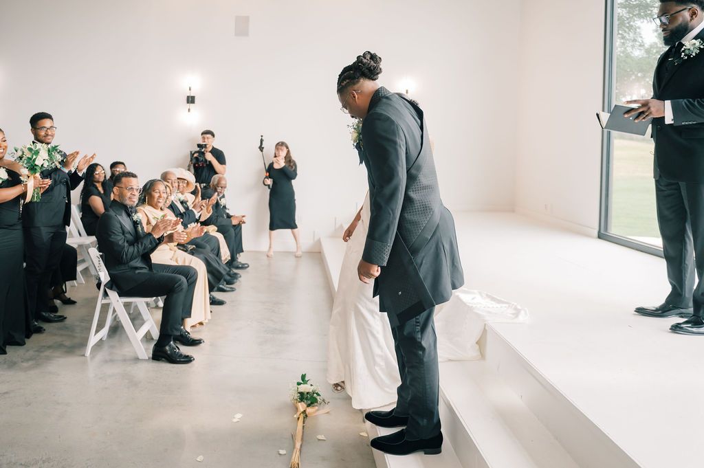 Bride and groom share a heartfelt bow during their wedding ceremony before seated guests.
