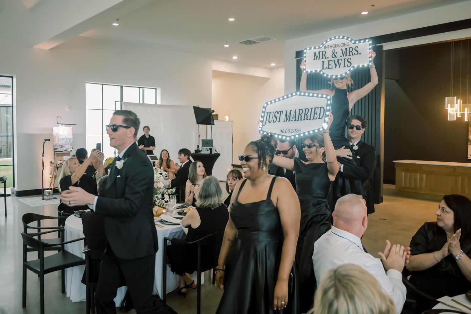 Wedding guests celebrating newlyweds Mr. and Mrs. Lewis with Just Married signs at reception.