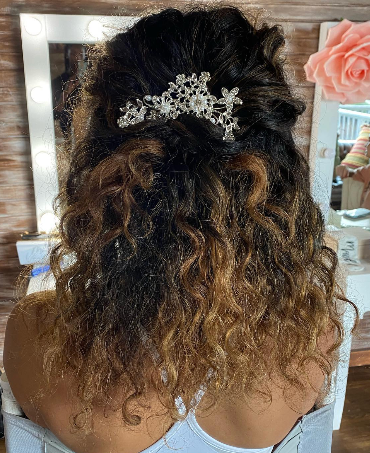 Curly ombre half-up hairstyle adorned with a sparkling crystal hair comb, perfect for weddings or formal events.