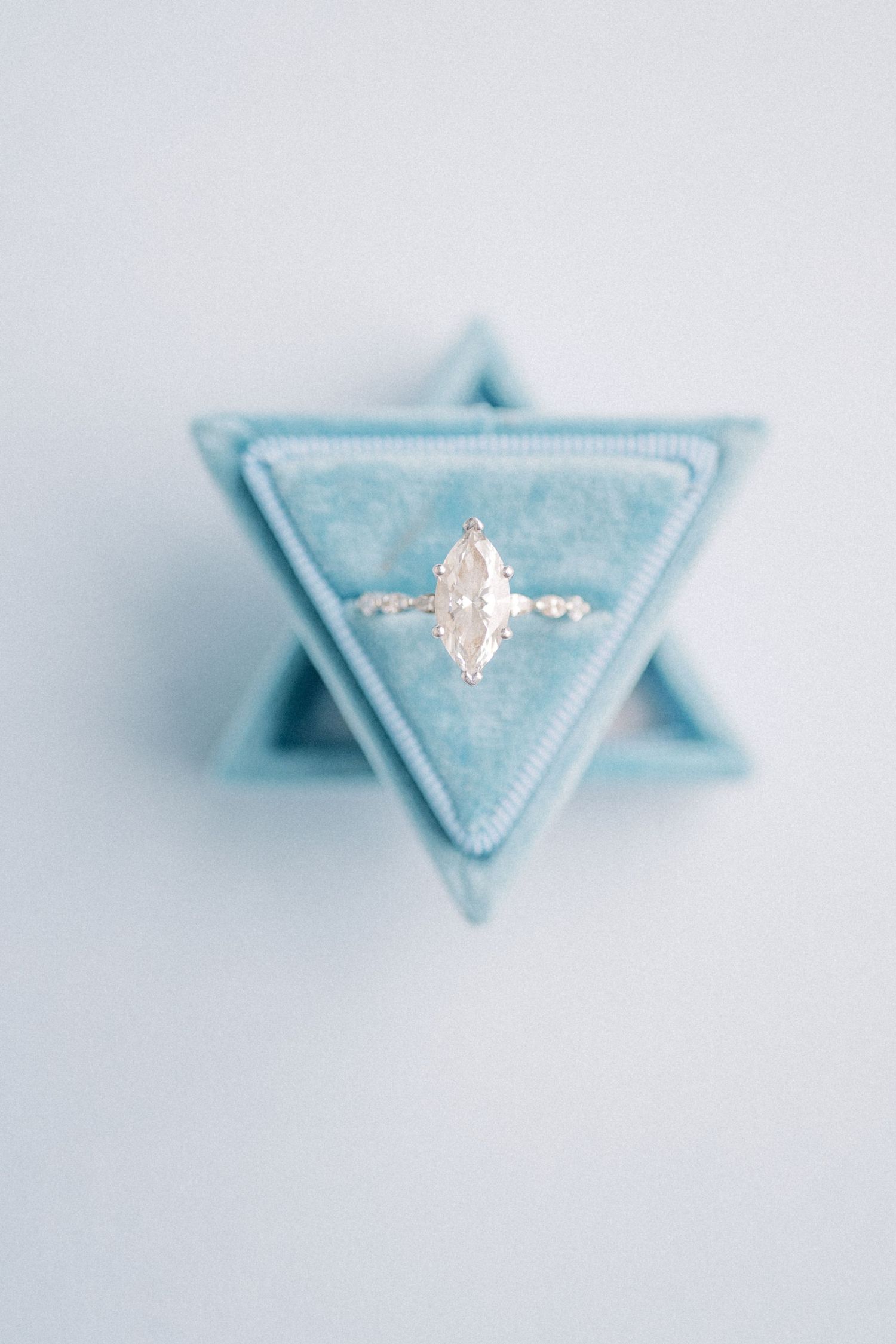 Marquise diamond engagement ring displayed in a light blue velvet triangular ring box.