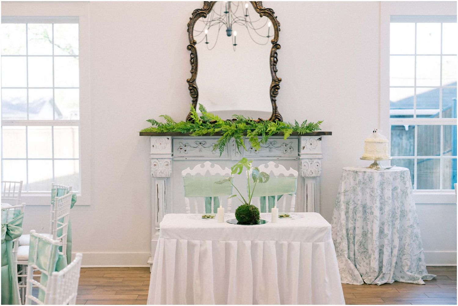 Elegant white wedding reception venue with draped fabric, floral arrangements and crystal chandeliers.