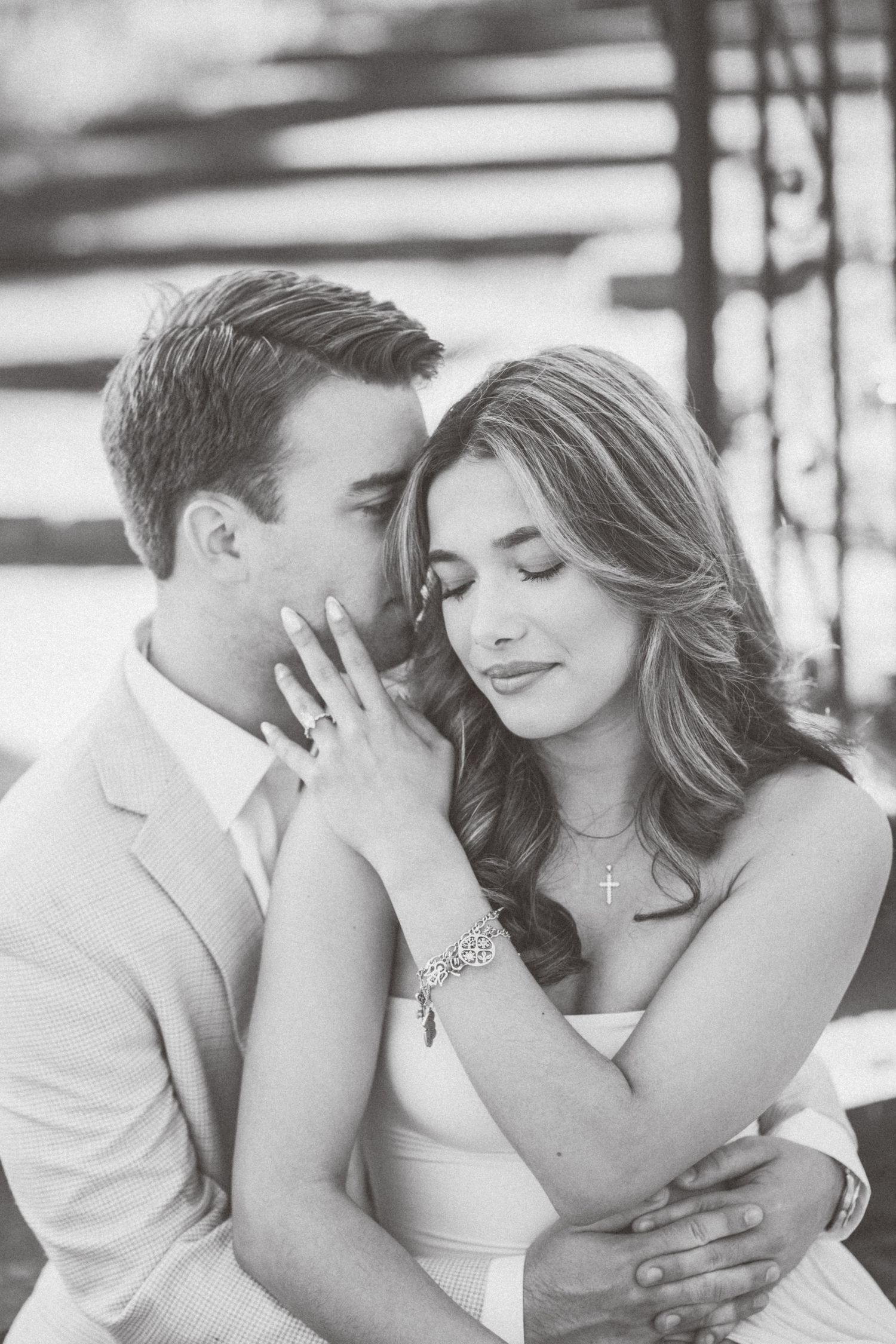 A romantic black and white portrait of a couple in wedding attire sharing an intimate moment together.