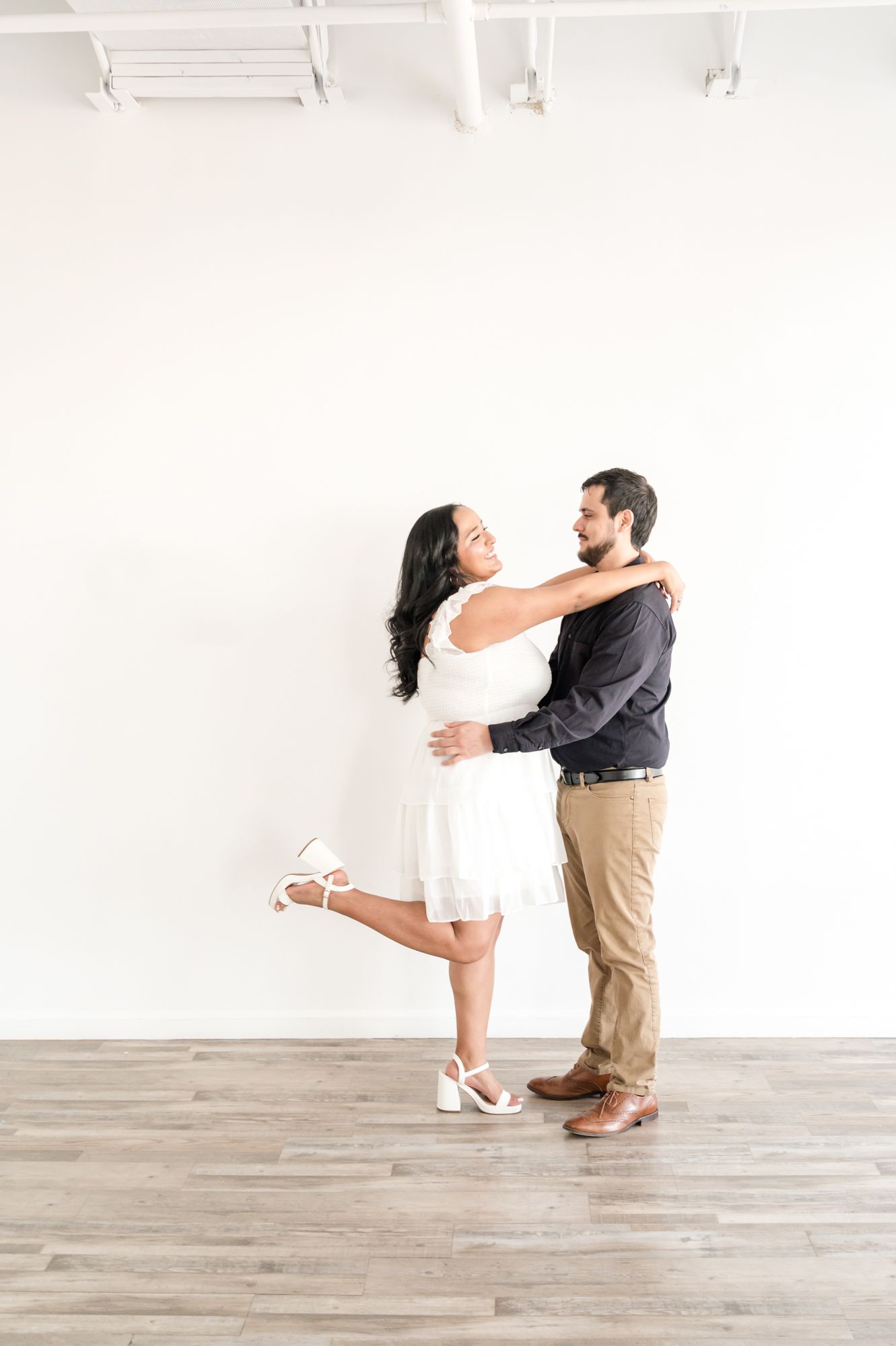 Dancing couple in casual attire performing dips and spins on a light wooden floor.