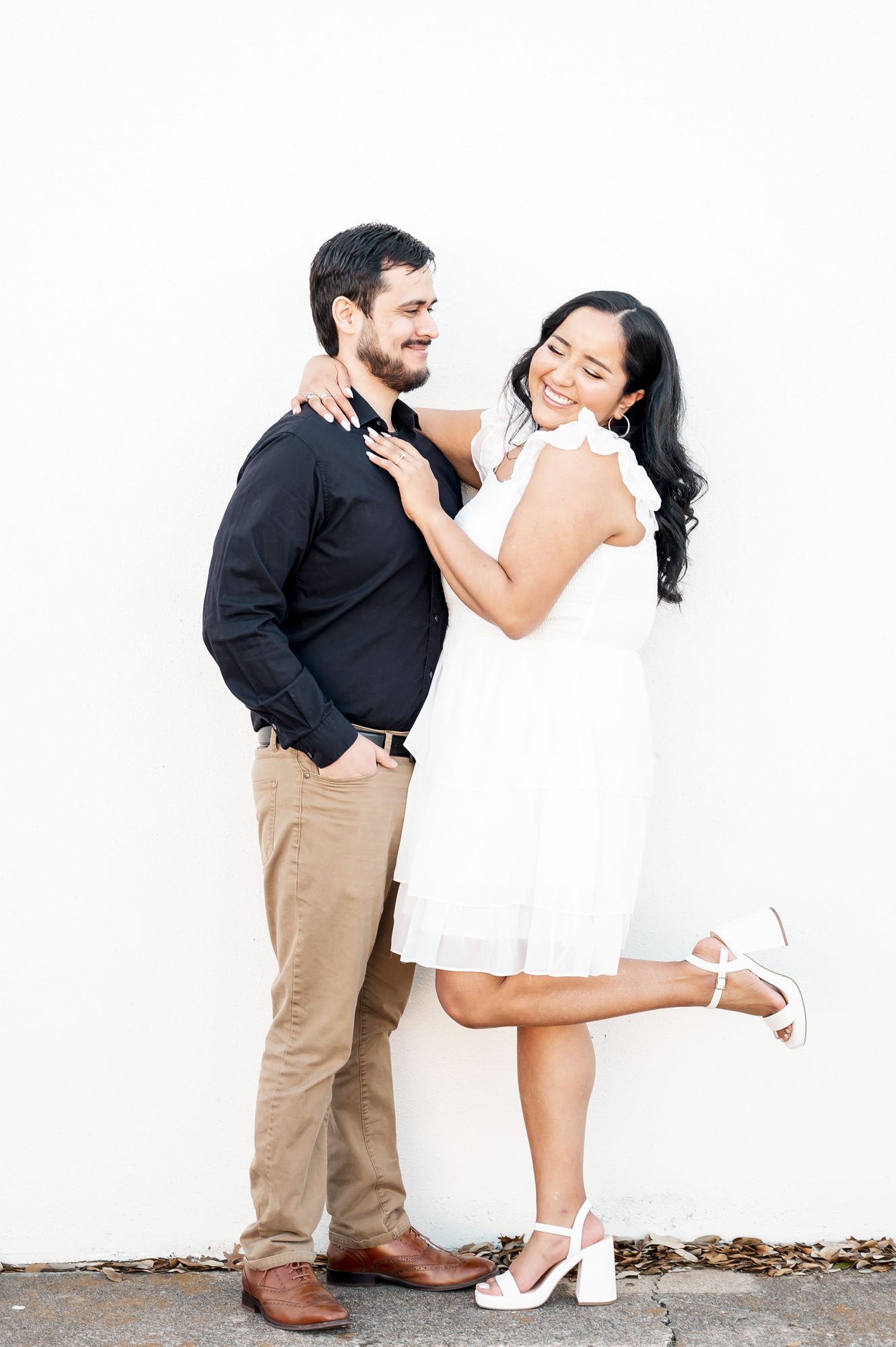 A couple shares playful and affectionate moments in a minimalist white setting.