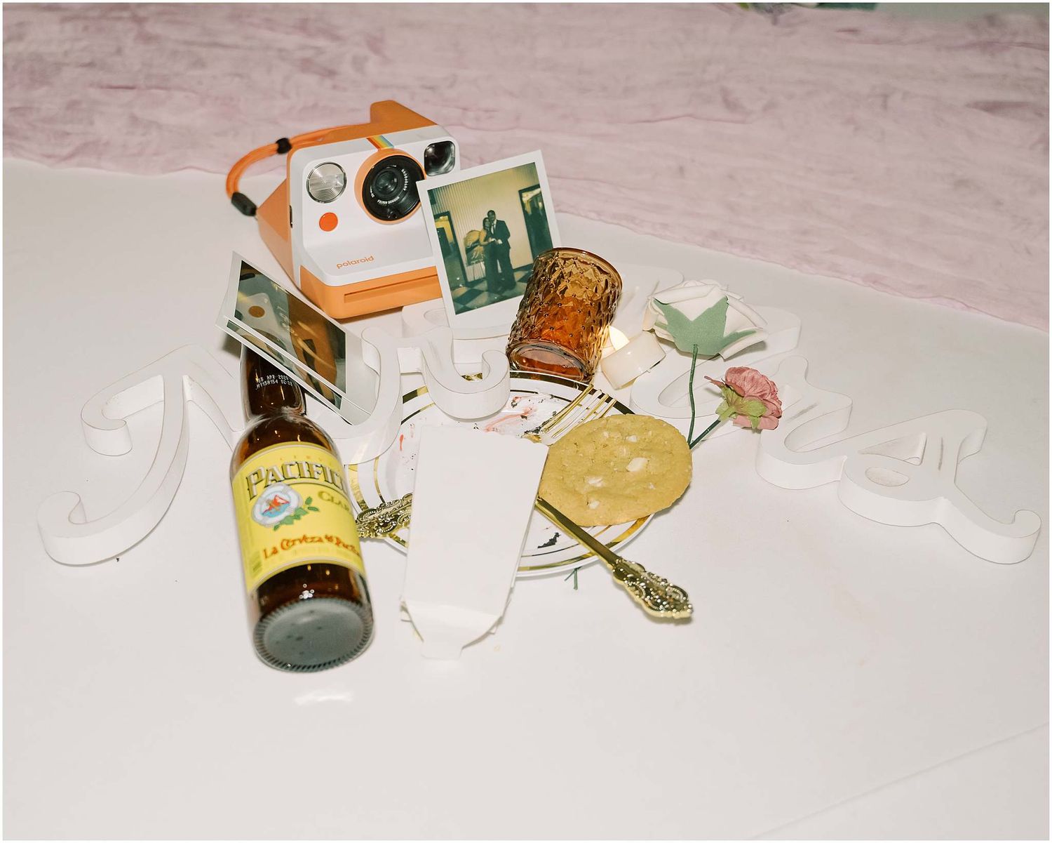Collection of wedding favors and decorative items arranged on a light pink surface.