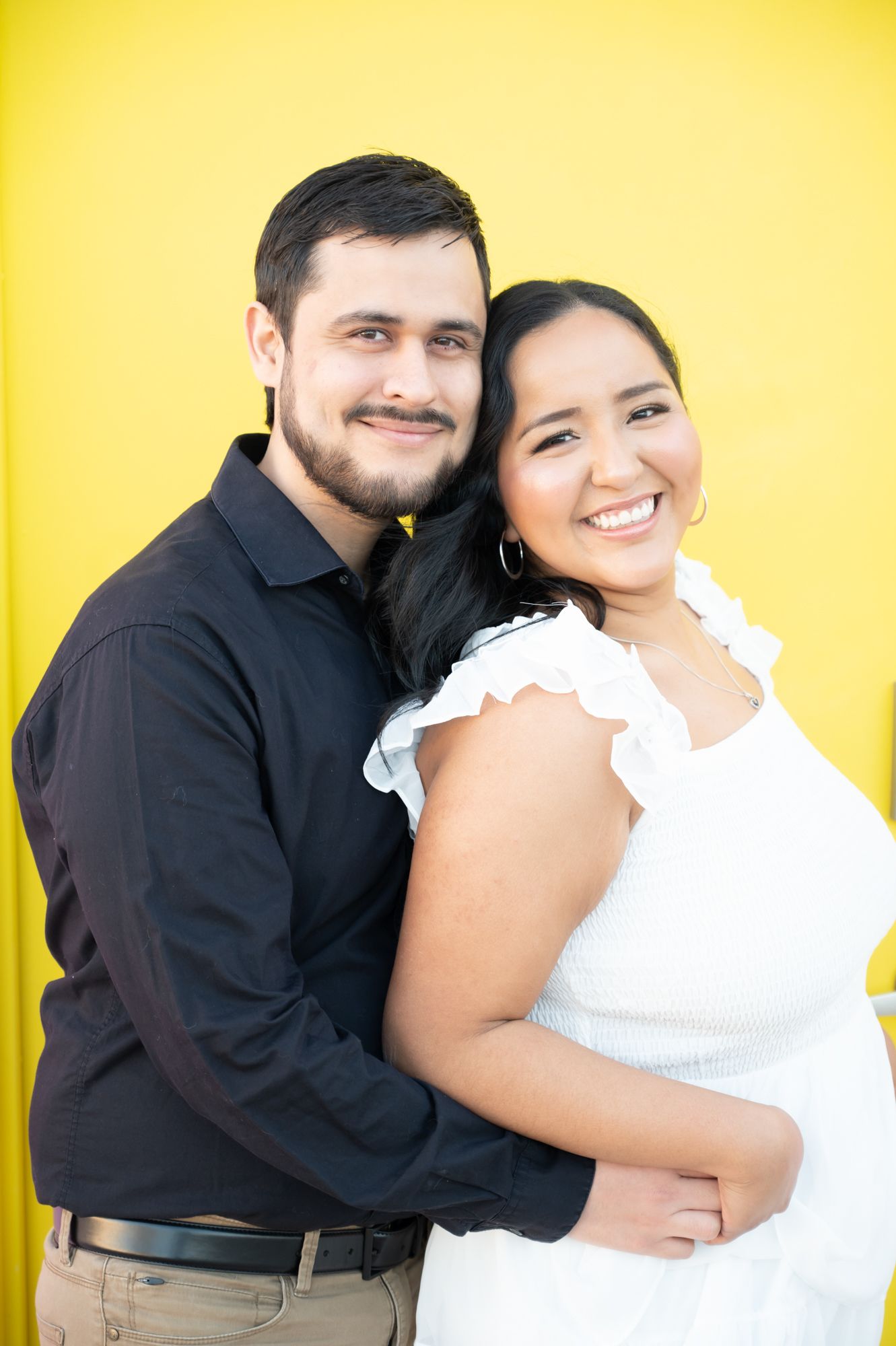A couple embraces and laughs against a bright yellow background in a series of candid photos.