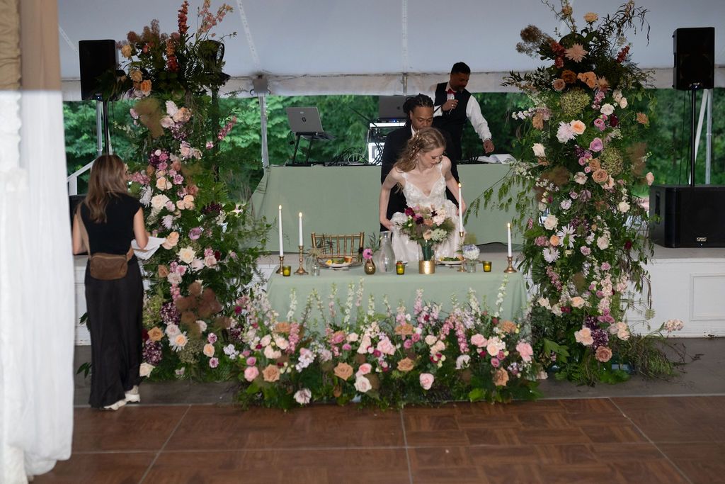 Bride and groom seated at a sweetheart table adorned with lush pink floral arrangements at wedding reception.