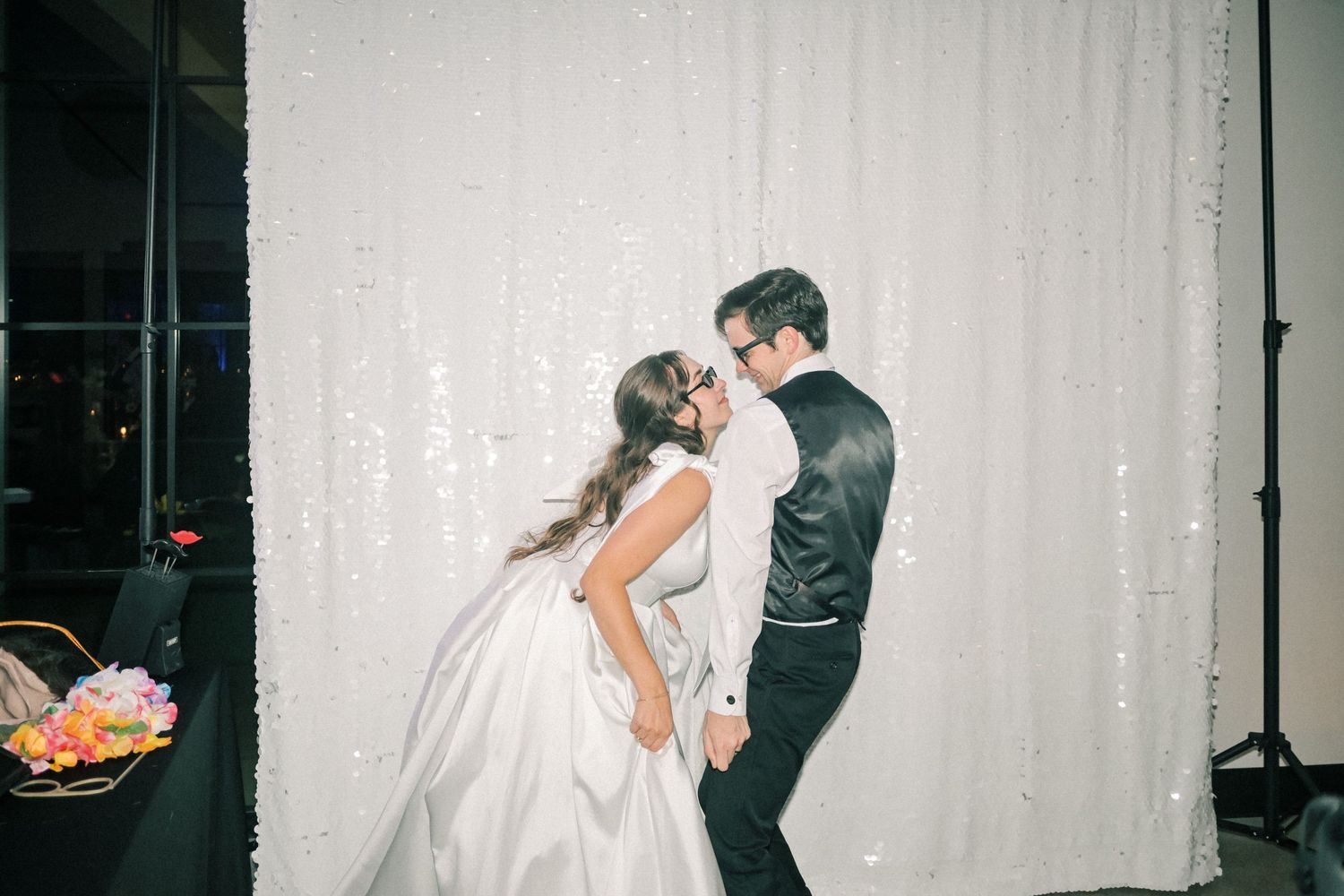 Bride and groom share a romantic slow dance in front of a sequin backdrop.
