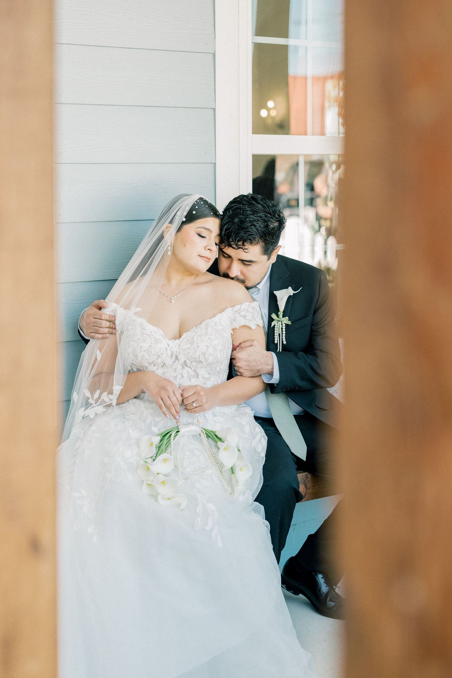 A romantic wedding couple embraces on their special day, with the bride wearing an elegant white lace gown.